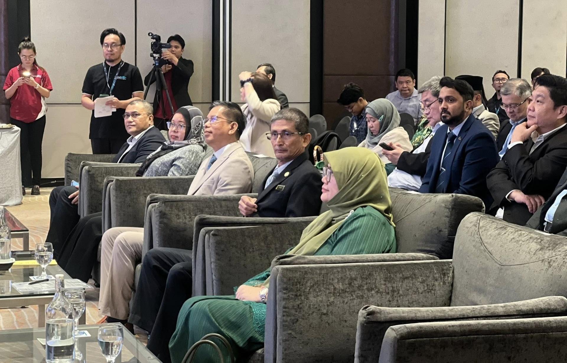 公用事业及电信部副常务秘书法吉尔沙哈（前排右2）代表不克出席的部长拿督斯里朱莱希纳拉威宣读其讲稿。