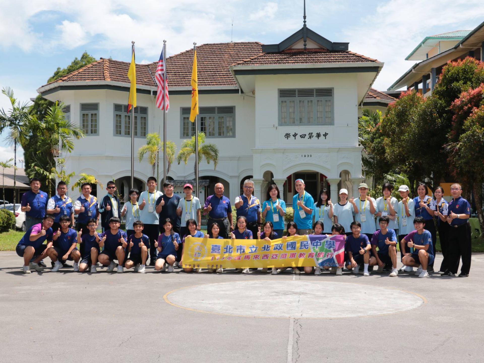 台北北政国中洪素真校长与12位师生在抵达四中校园时受到四中校长官晨阳、行政主任及该校童军教练与师生热烈欢迎，并在校园前大合照留念。