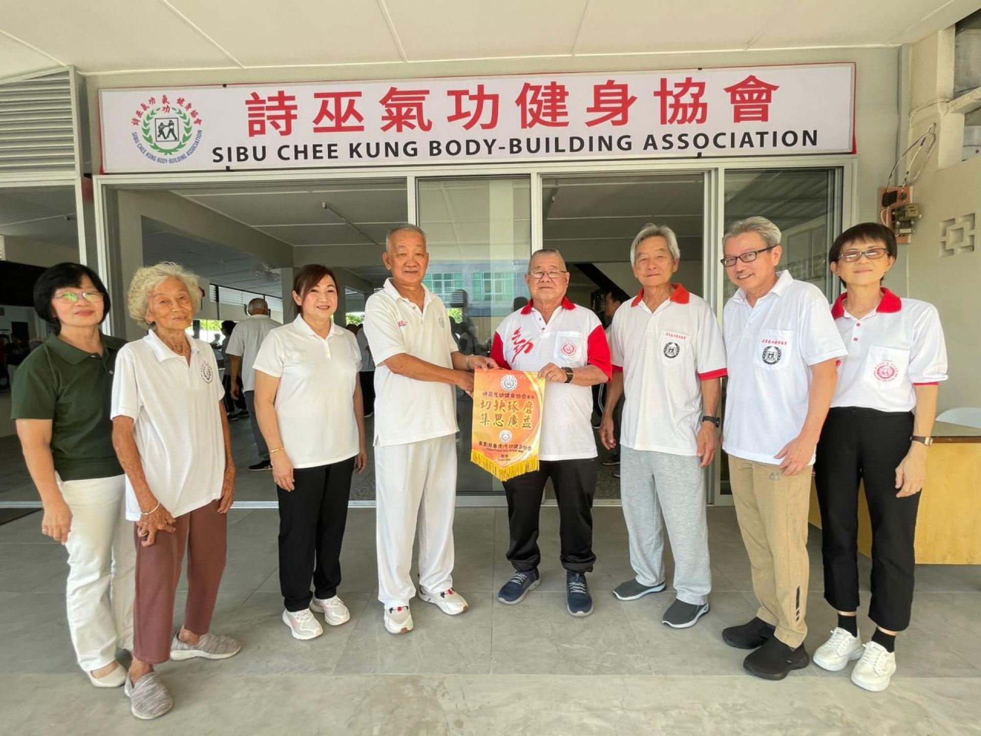 诗巫气功健身协会气功师父刘仁铭（左4）接收美里（郑春虎）气功健身协会署理主席蔡顺安（  右4）赠送的纪念锦旗。左3为诗巫气功健身协会主席许毓雯，右3为美里（郑春虎）气功健身协会交流活动团  长温锦松。