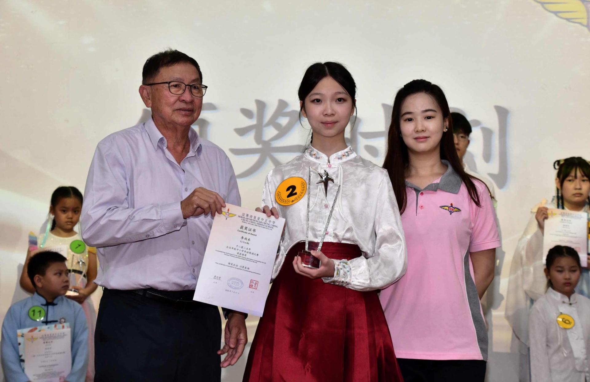 P250717LYK01A：李雨禾（前中）从颁奖嘉宾手中接过中学组亚军奖。