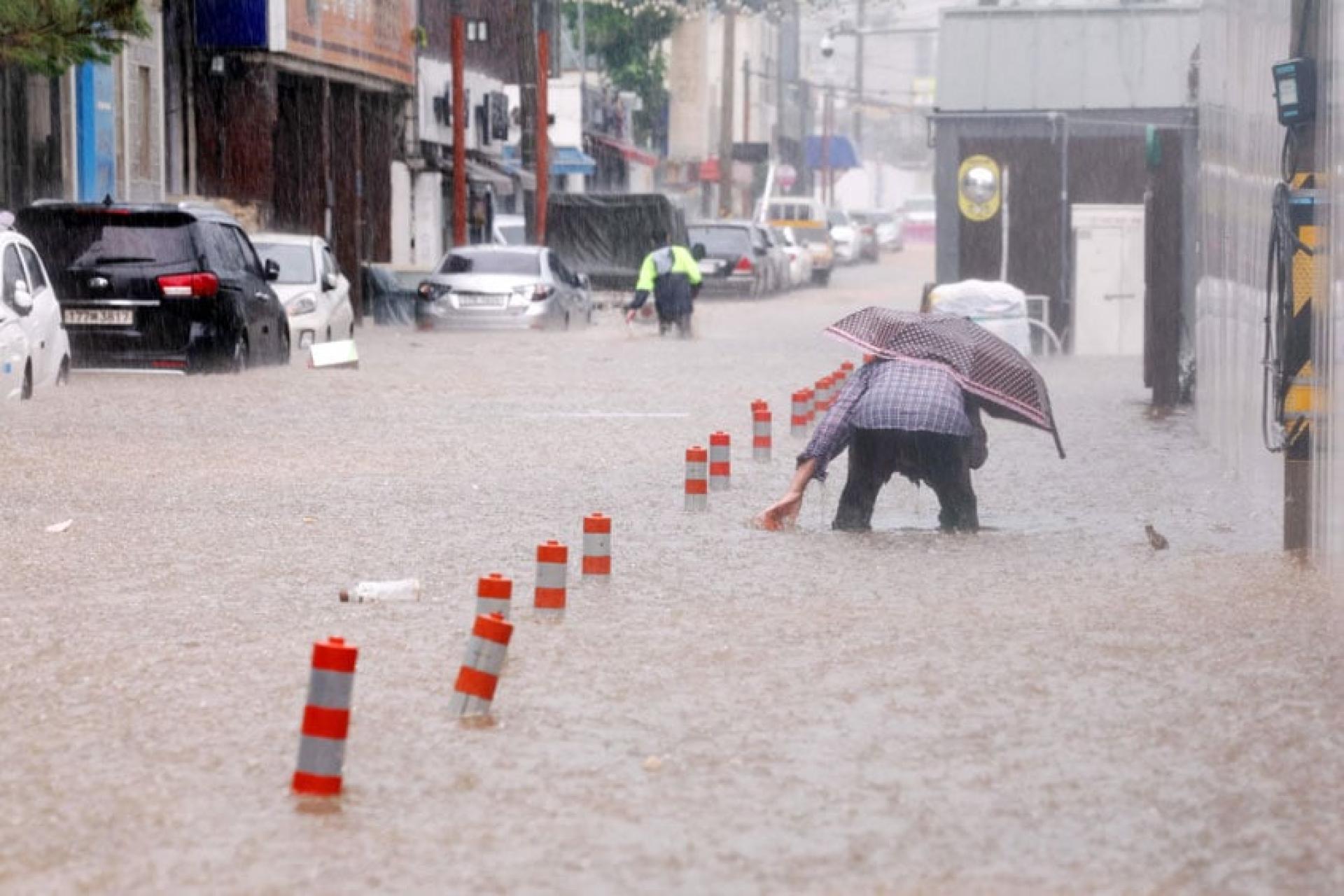 在光州，一名男子穿过被暴雨淹没的街道。