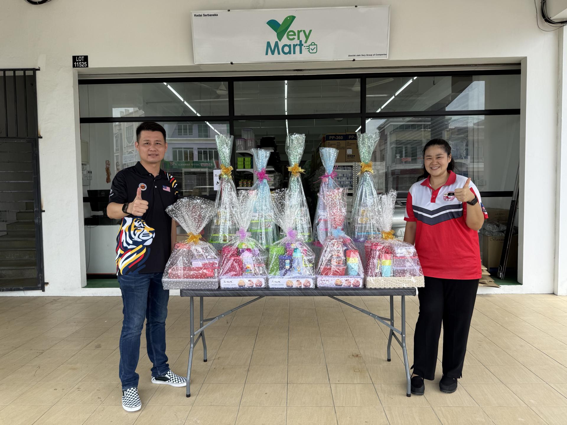 国家体育理事会董事林思健律师（左）配合 Very Mart 捐赠10个礼篮，并由瓜拉峇南第二国小老师沈明荣接收。