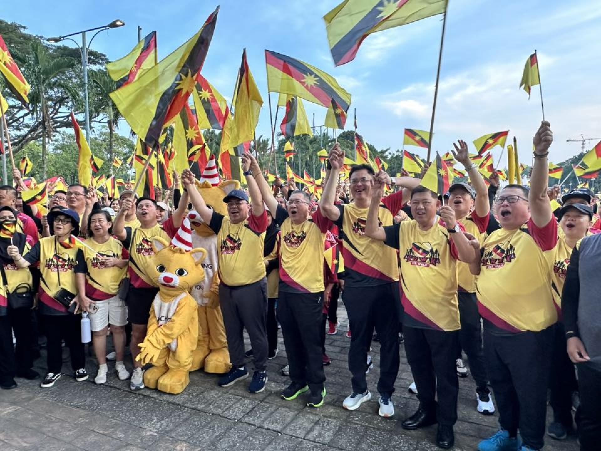 南市市长拿督黄鸿圣（右4）、北市市长拿督希尔米奥斯曼（右5）及巴达旺市议会主席陈开（右3）等人与参与者高昂的挥动砂拉越旗帜，欢庆砂拉越日的到来。
