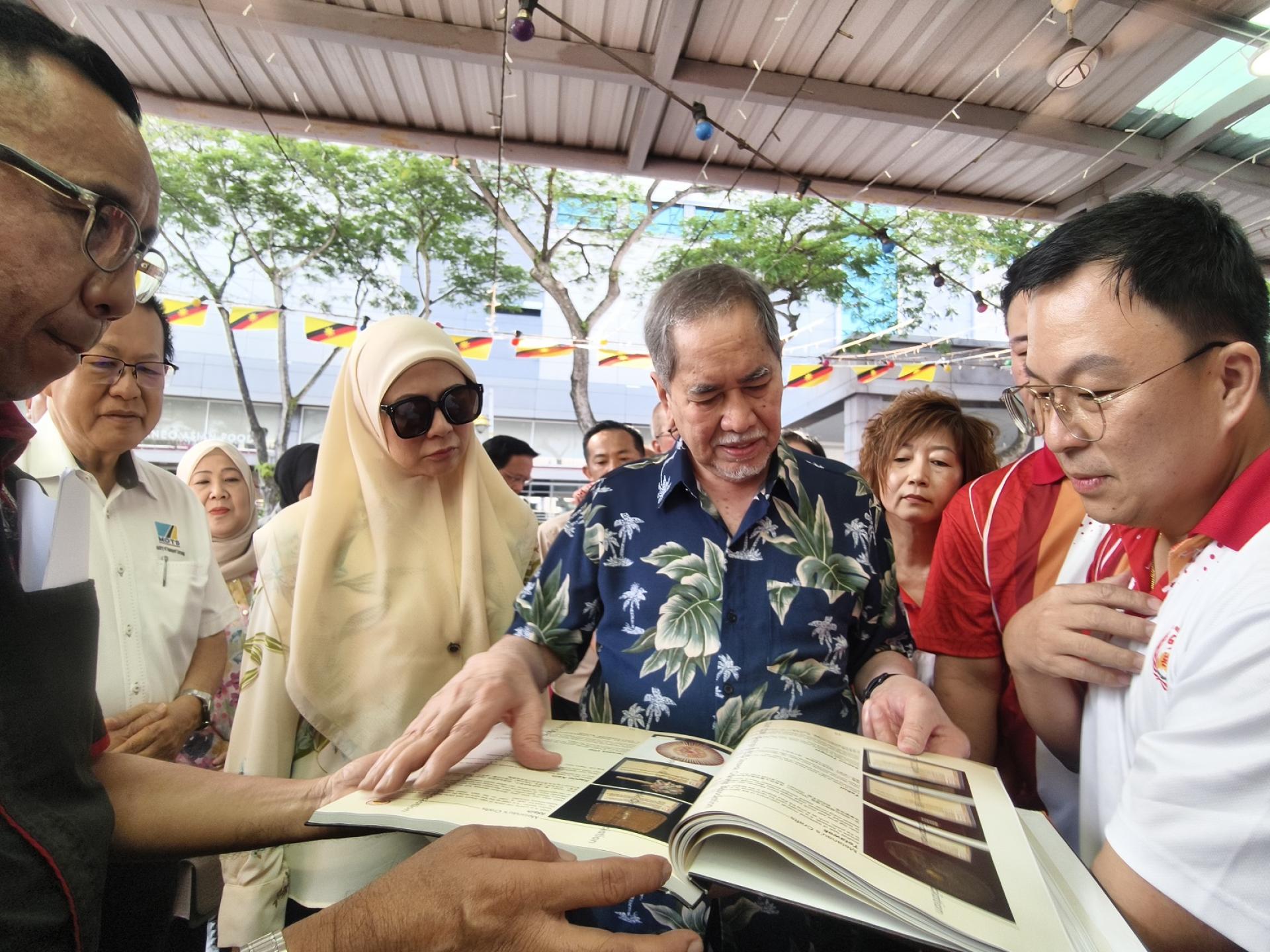 砂拉越华人公会会长李天送（右）与砂元首敦旺朱乃迪伉俪分享该会出版的《探索砂拉越民族  工艺》图书集。左起为美里卡达央族协会主席莫哈末阿都拉及砂拉越交通部长拿督李景胜。