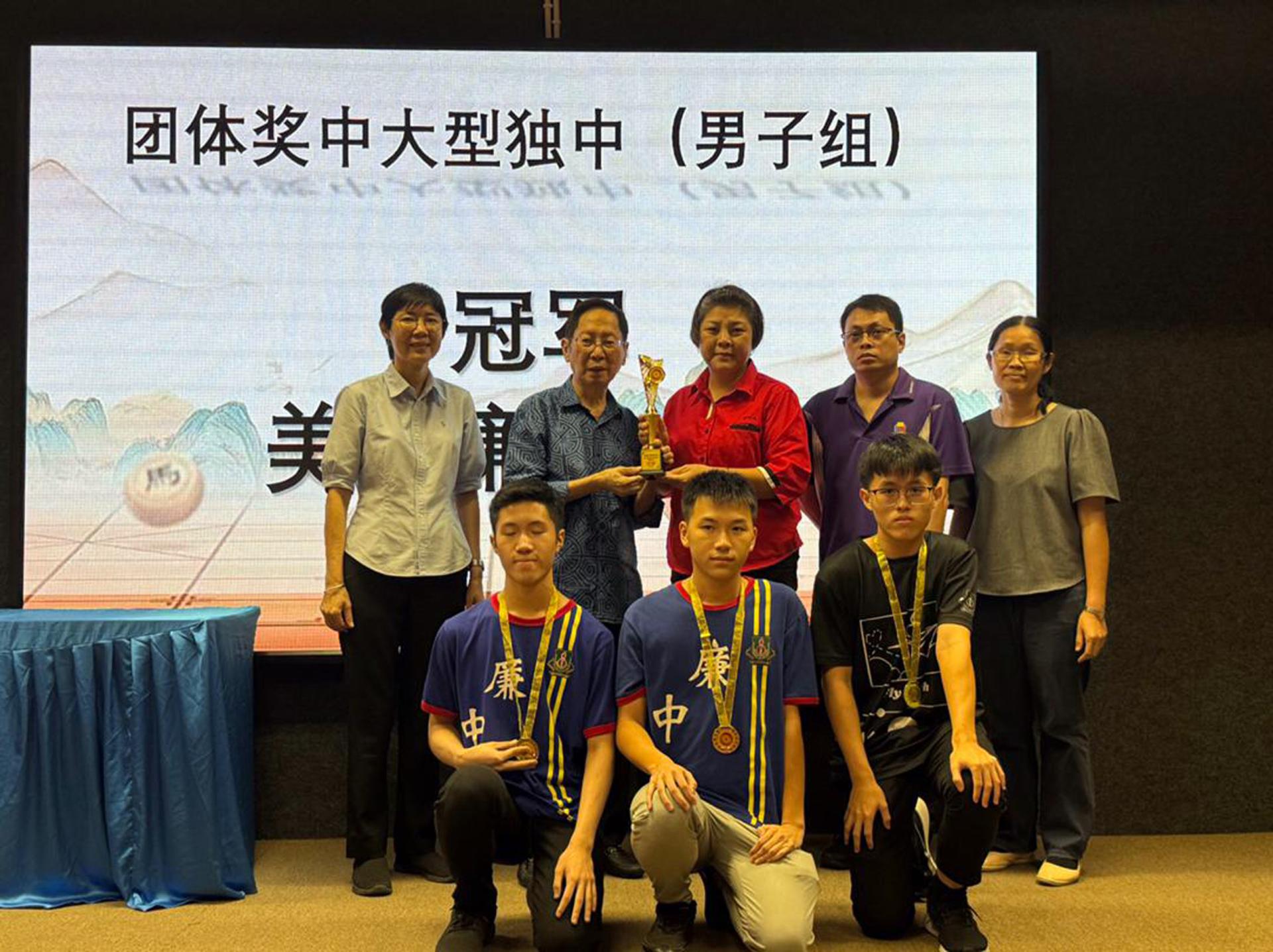 砂拉越华文独中董事联合会主席天猛公刘利民（左2）将男子组团体冠军奖杯颁予带队老师黄菊香（左3），并与3位得奖学生合影留念。
