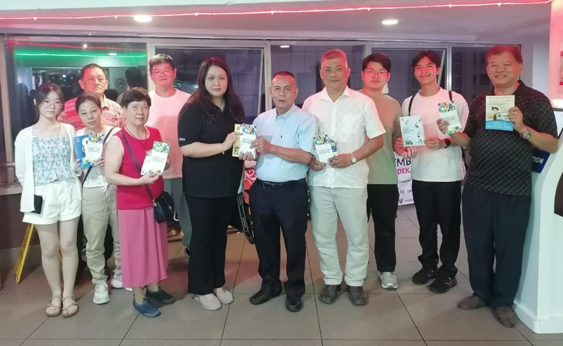 甲必丹林传政（右5）由联邦新闻局官员容巧妃手中接过反诈骗手册。