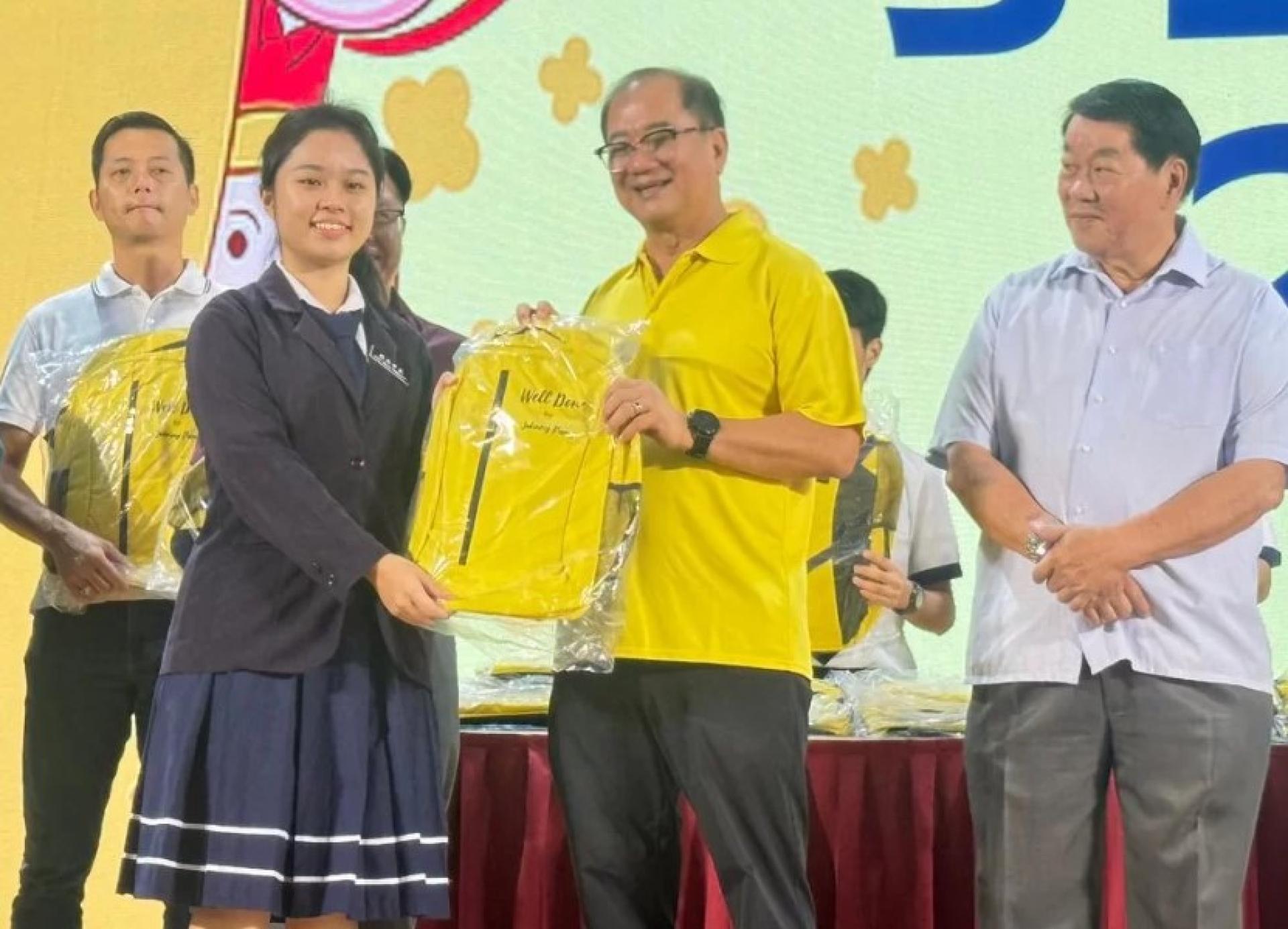 Pang handing over a school bag to one of the students from SM Kai Dee Bintulu.