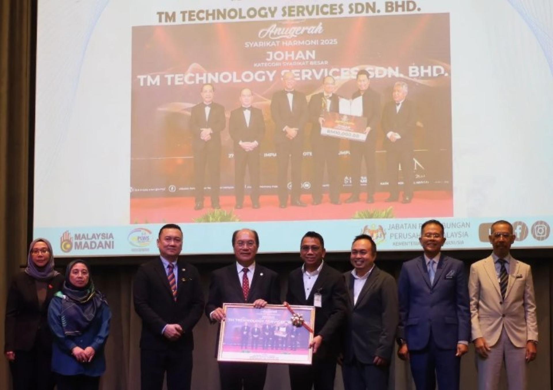 拿督格拉瓦嘉拉在“2025年砂拉越企业和谐计划”活动上，向TM Technology Services有限公司代表颁赠纪念品，右为马来西亚劳资关系局副总监阿米努丁。