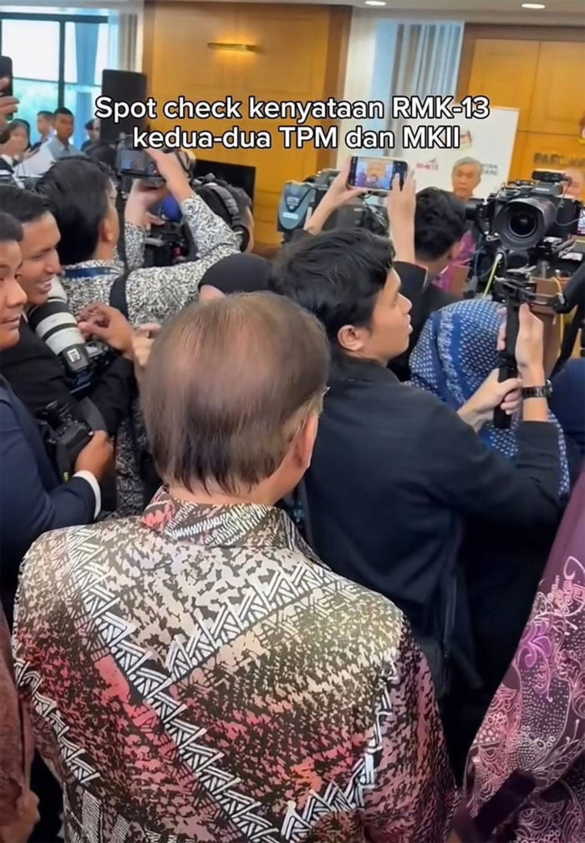安华（背对镜头者）“突击检查”副首相和第二财长就《第13大马计划》召开的记者会。