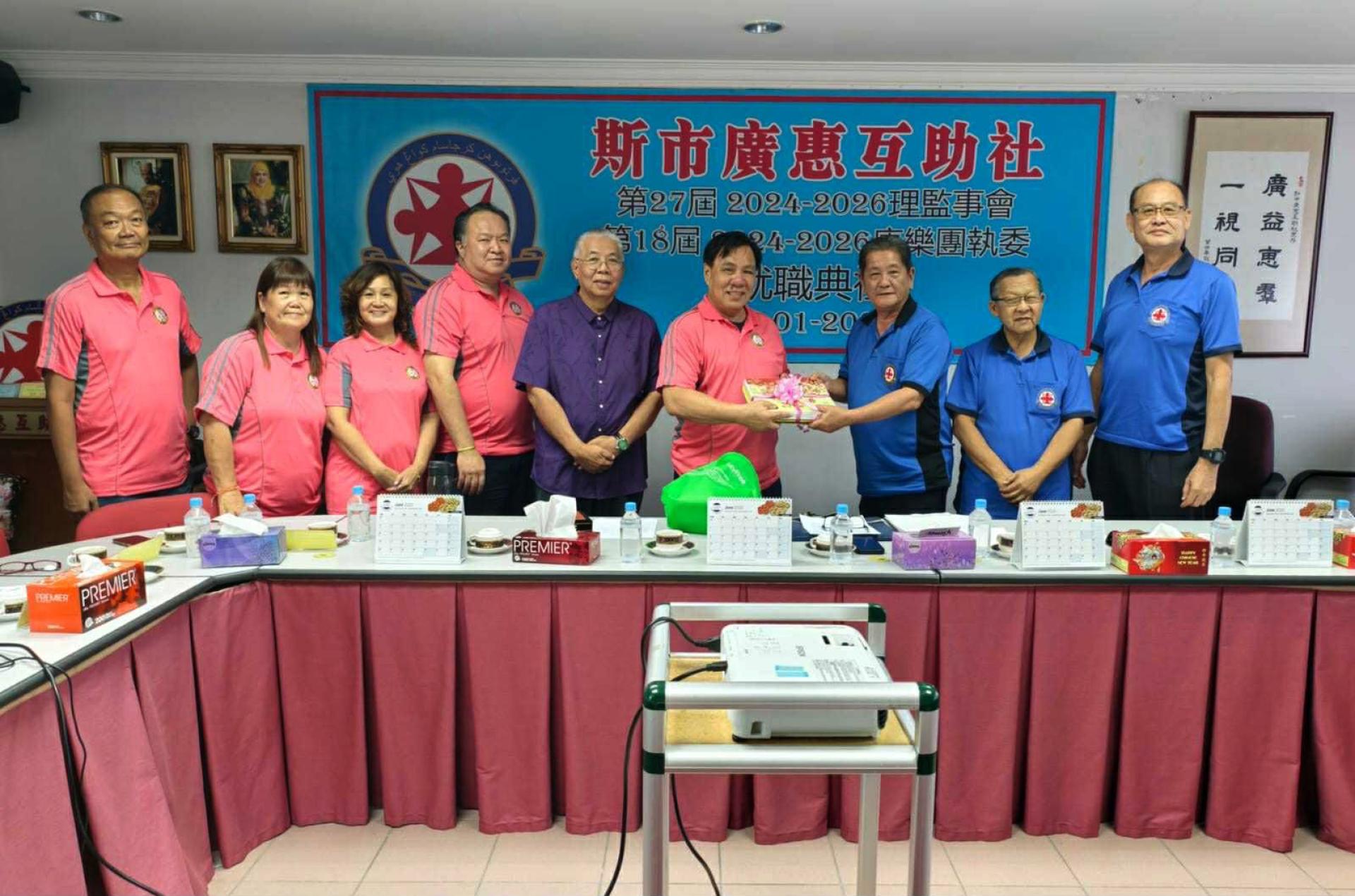 叶天福主席（右三）代表斯市广惠互助社赠送《广惠社讯》于纳闽广惠肇会馆，由会长曾保存（左6）代表接收。