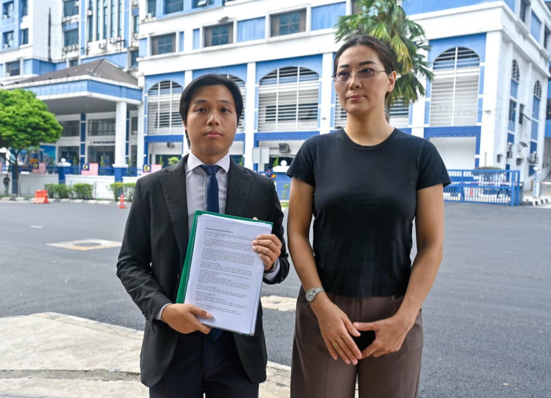 米亚（右）在吴佳豫在警局外出示声明和拍照。