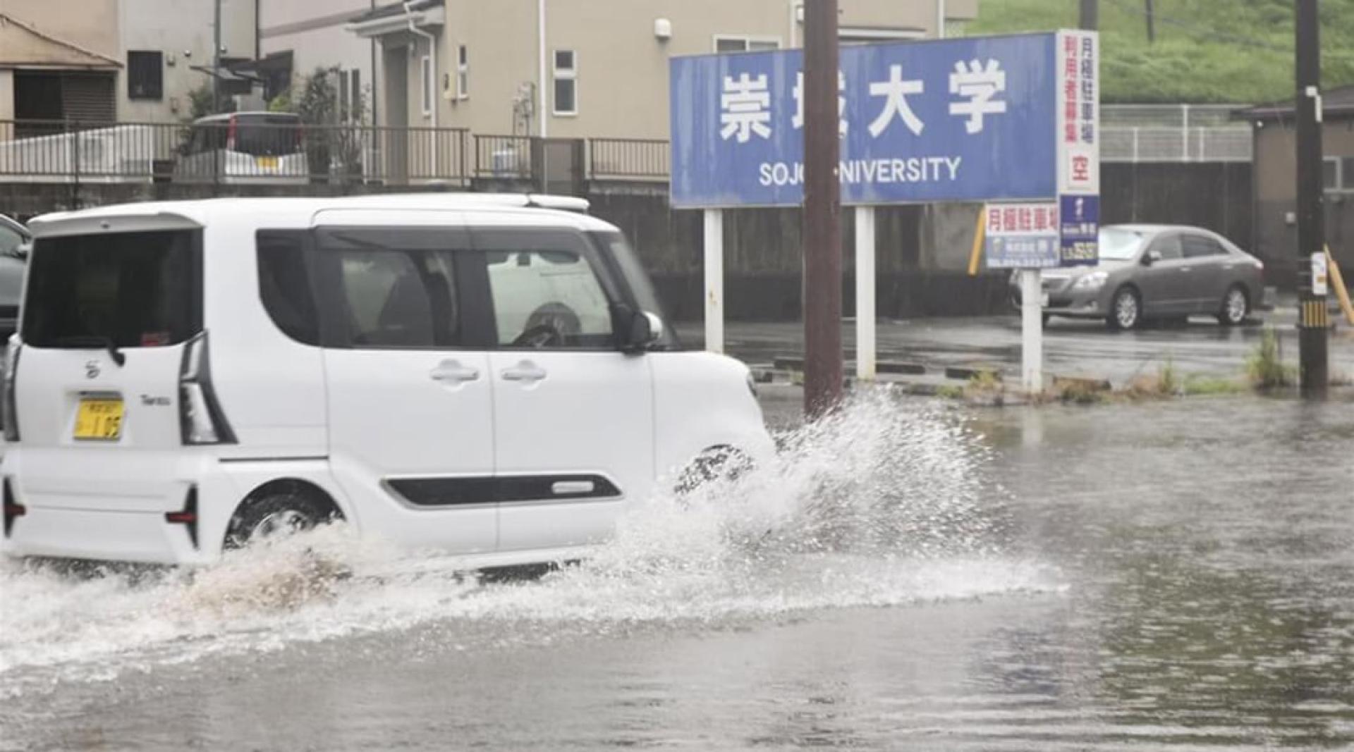 日本熊本市一辆私家车11日在淹水地区行驶。