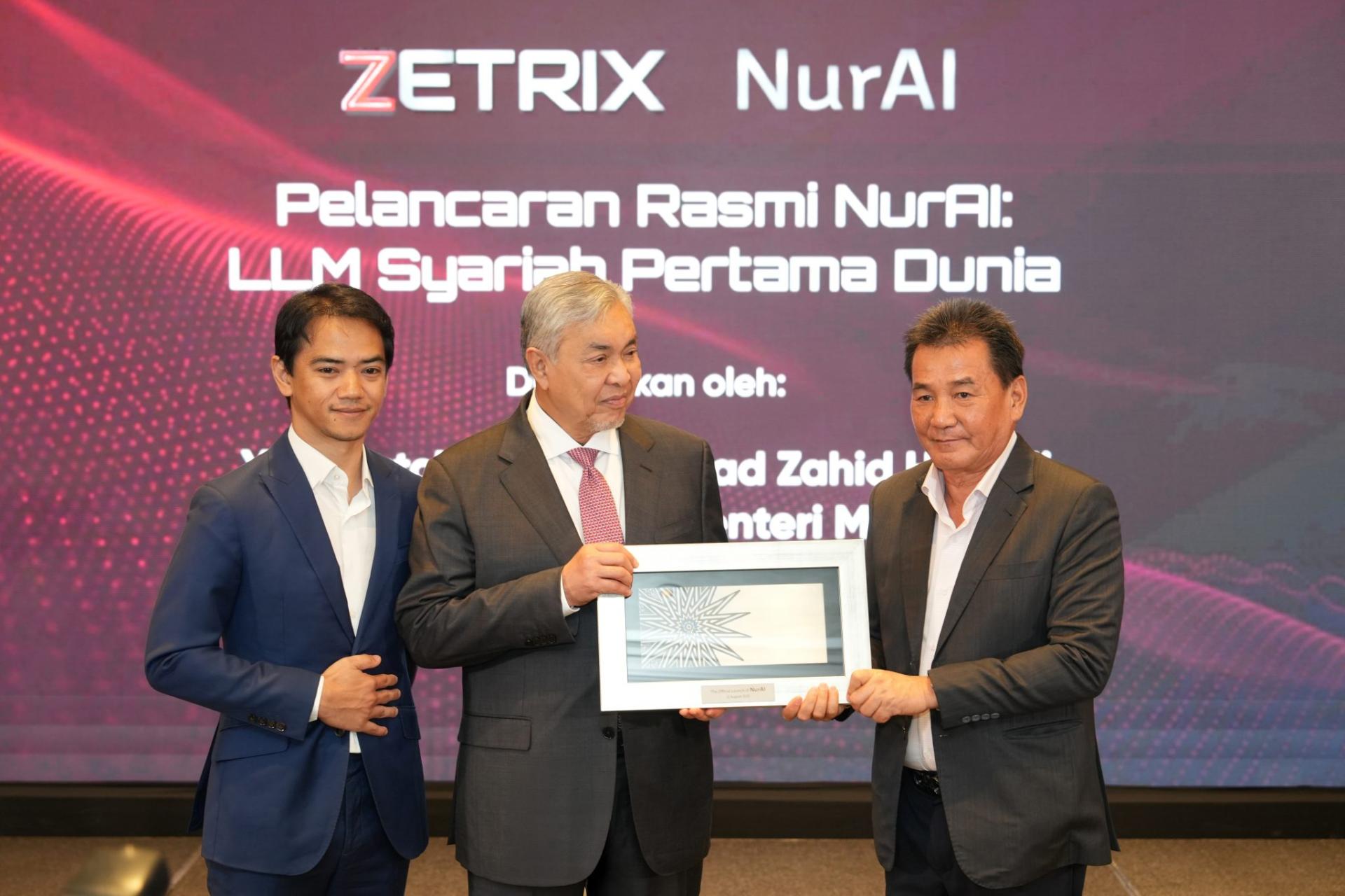 莫哈末占米黄（右）颁发纪念品给阿末扎希（中）。左为Zetrix联合创办人拿督法兹里。