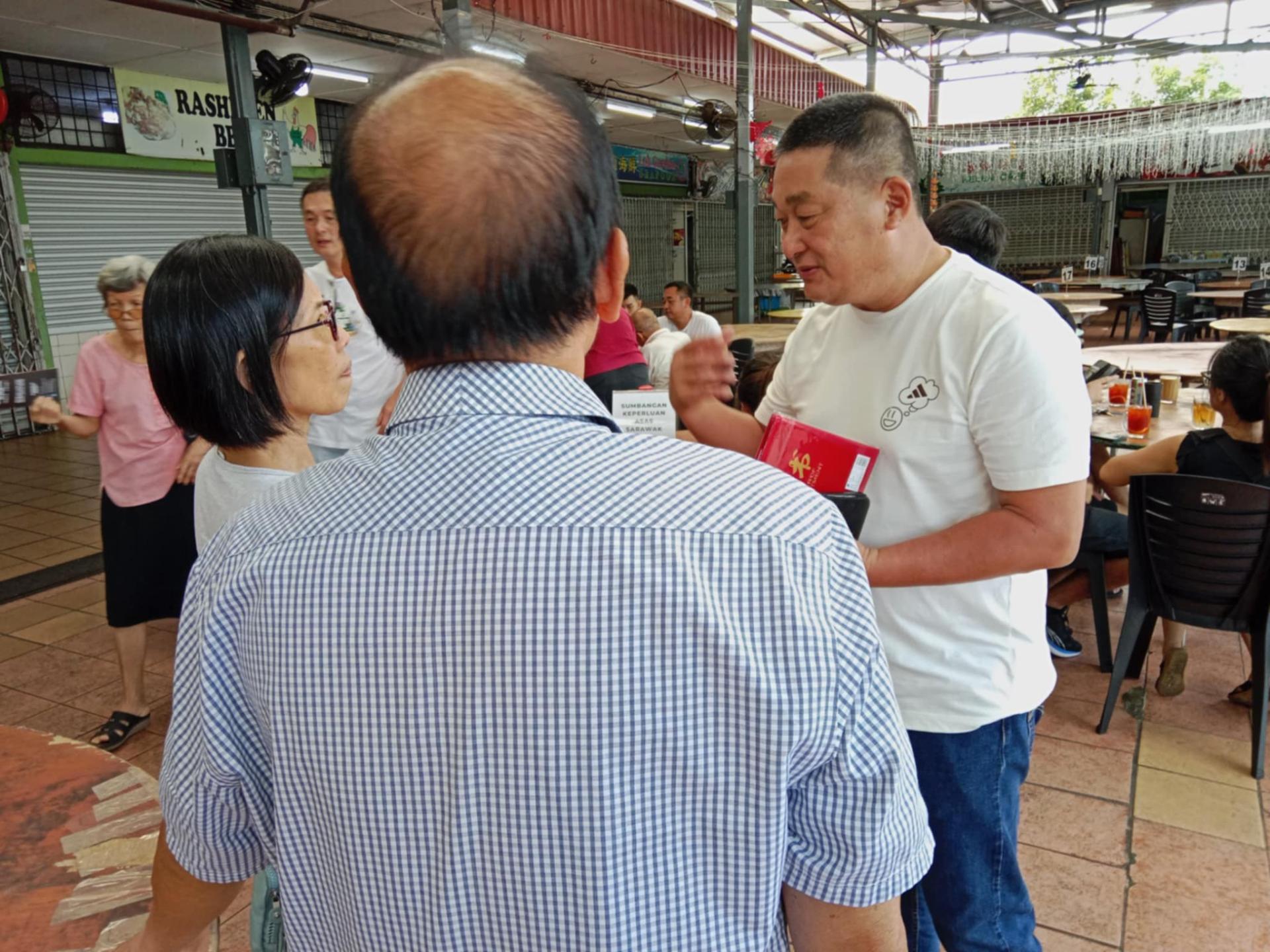巴都林当区议员施志豪（右）向民众讲解砂政府推行的各项惠民项目，并解答民众提问。