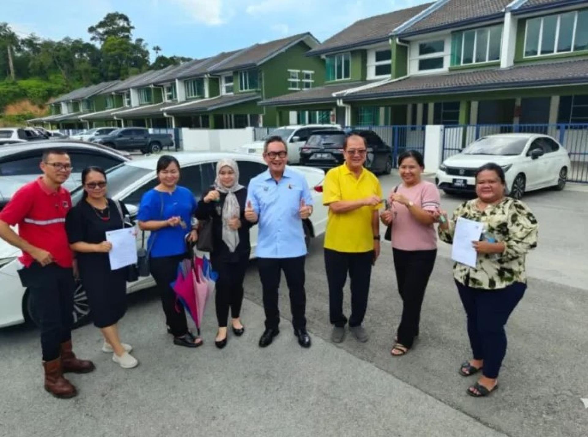 砂副部长程明智（Datuk Michael Tiang Ming Tee）（左5）与丹绒巴都州议员 潘隆铭（Johnny Pang）（右3）在民都鲁，与首批拿到钥匙的业主合影，共同见证延宕七年的项目交屋时刻。