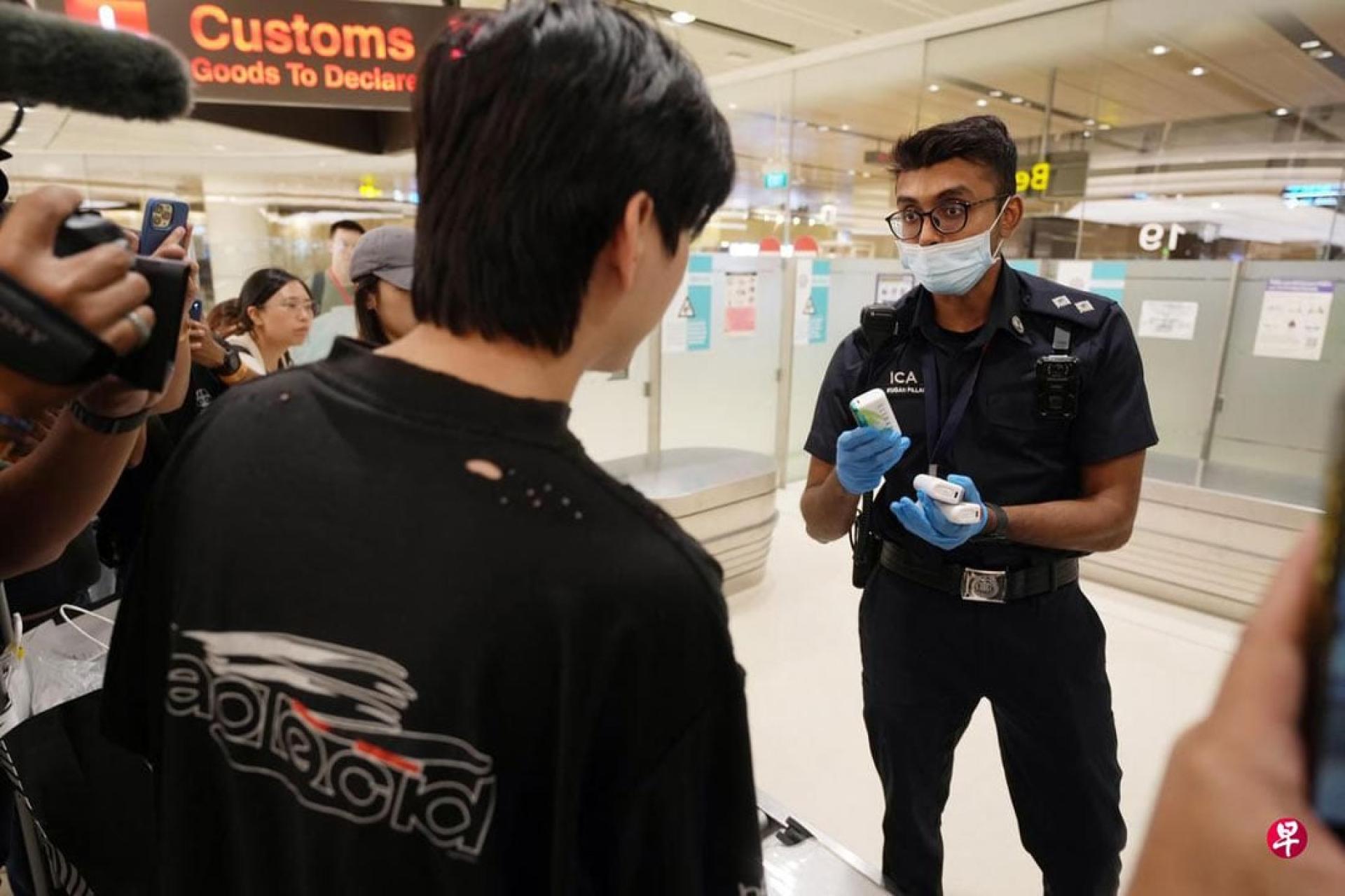 在樟宜机场第一搭客大厦，一对情侣主动上交三支电子烟。移民局人员警告他们后，当场把电子烟丢进回收桶。 （图：联合早报）