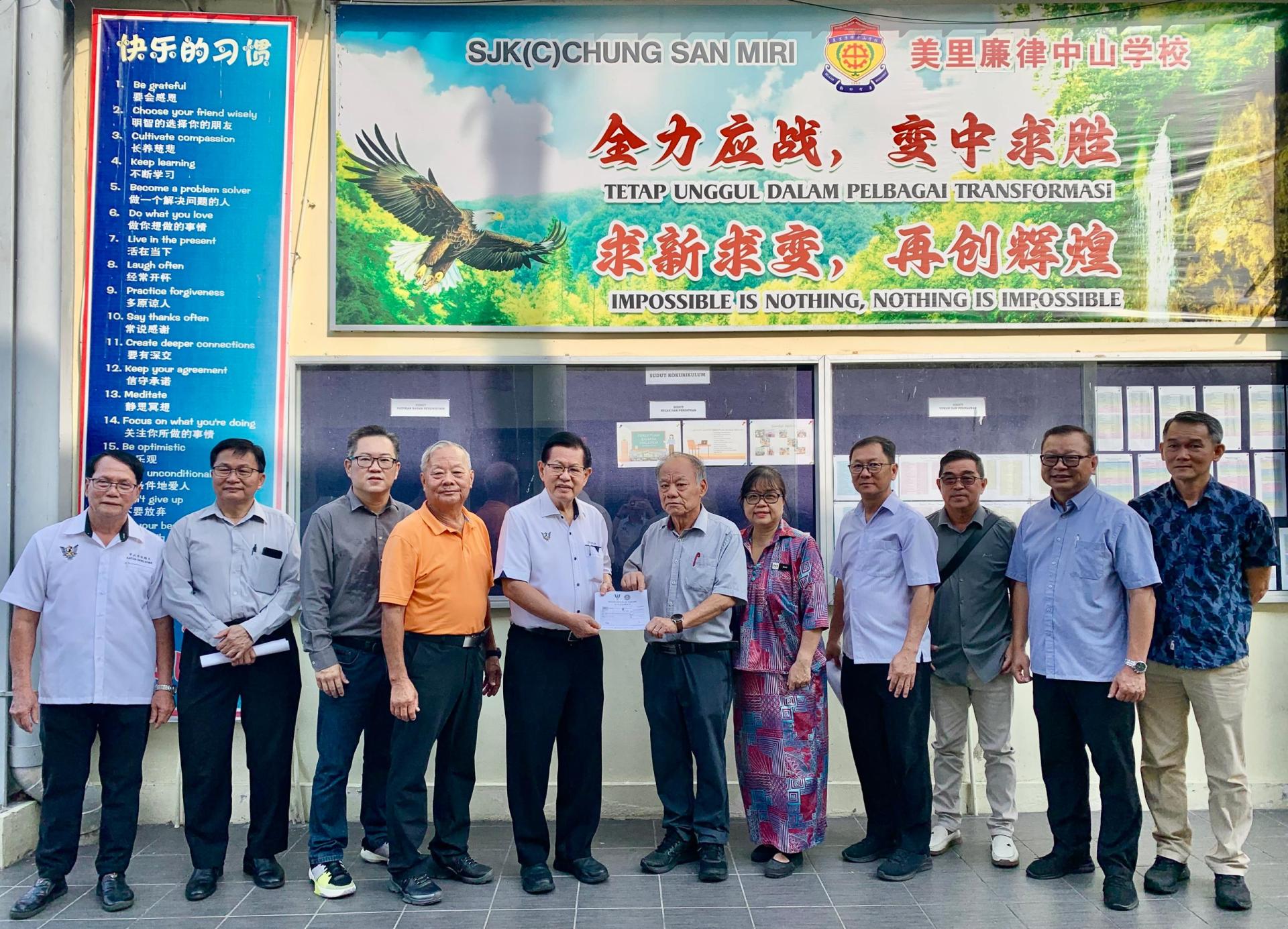 史纳汀区州议员拿督斯里李景胜（左5）移交3万令吉拨款给美里廉律中山小学，由董事长刘汉  平接取。左4为署理董事长拿督斯里刘久健等成员。