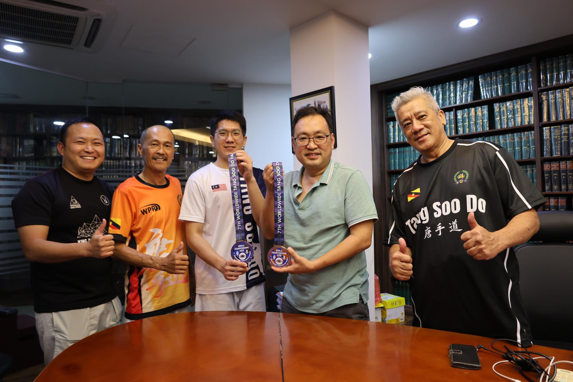 实旦宾国会议员张健仁（右2）与覃琪焕（中）展示两枚沉甸甸的战利品，欢庆胜利的喜悦。左起为张健仁特别助理江峰年、三马拉汉省唐手道协会财政邱昌永；右起为覃琪焕父亲兼教练覃懋农。