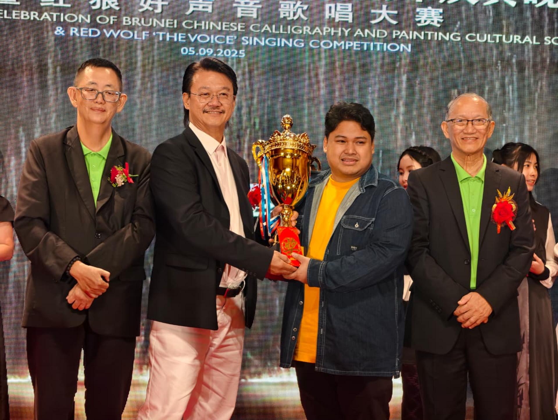 汶莱中华书画文化协会名誉顾问洪益祥颁发冠军奖杯予郑汶其，左一为杨镇声会长、右一为包平生副会长