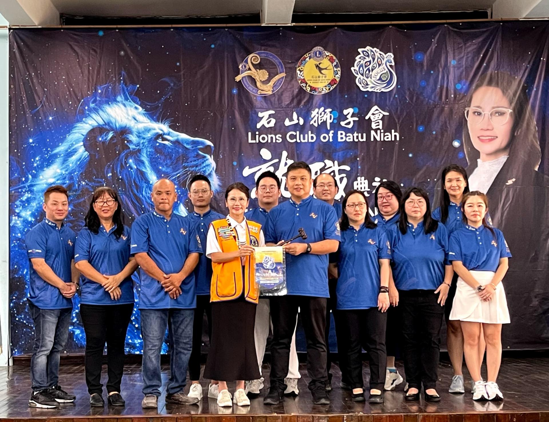 国际狮子会308A2区总监李秀萍（左5）将鸣钟槌子移交予石山狮子会会长何暐奇。