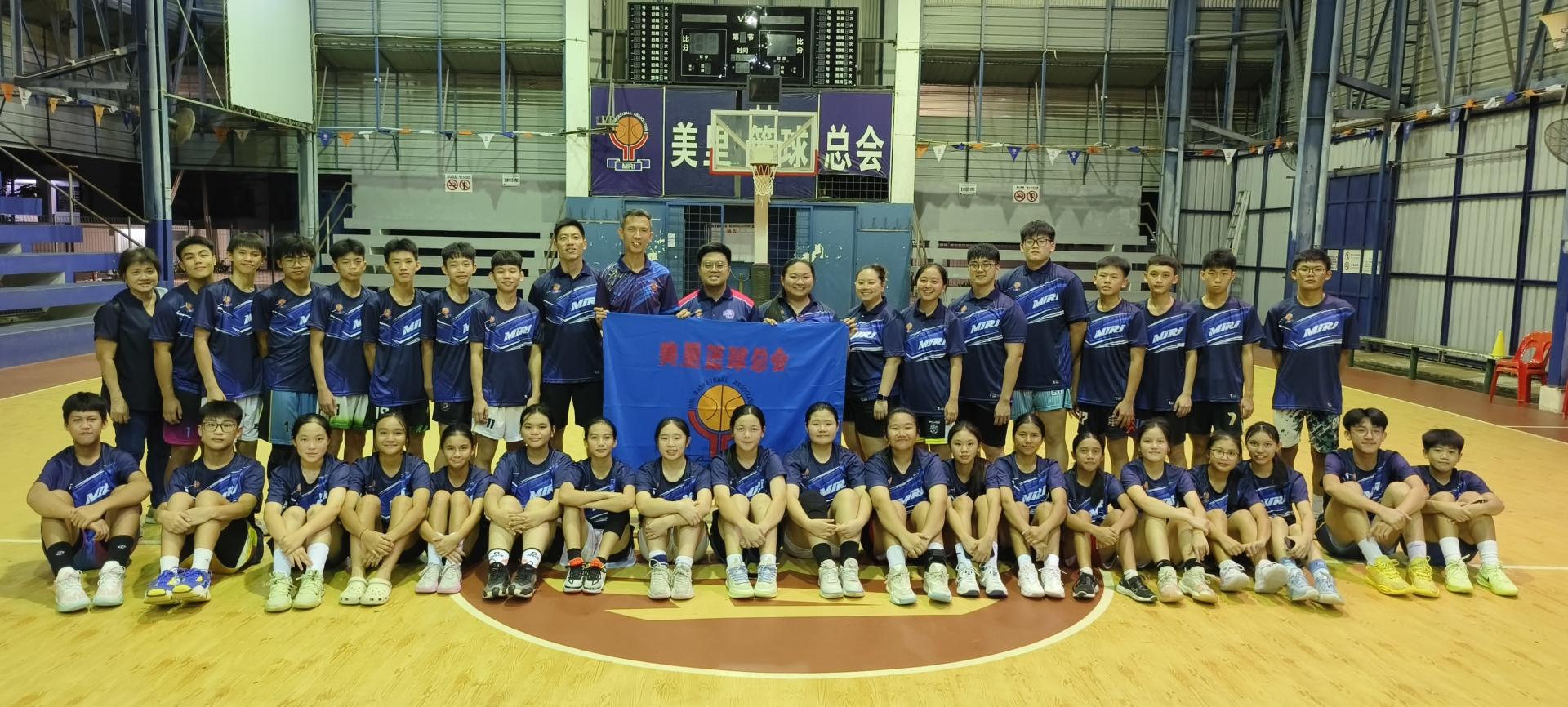 美里篮球总会主席廖国炜（站者左10）授旗予教练朱怡婧，并与全体15岁及以下中童男女球员合影。左11为赛会筹备会主席陈振杰。