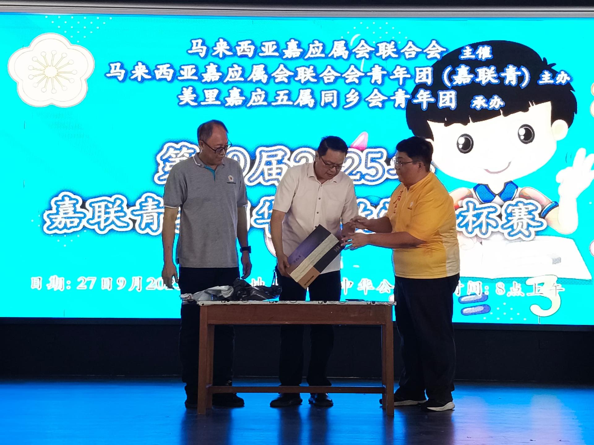 砂交通部长拿督斯里李景胜的代表彭小菶（中）为第39届嘉联青全国华小数学金杯赛美里区赛主持开幕揭封仪式。左为美里嘉应五属同乡会主席甲必丹梁振林，右为筹备会主席凌伟鹏。