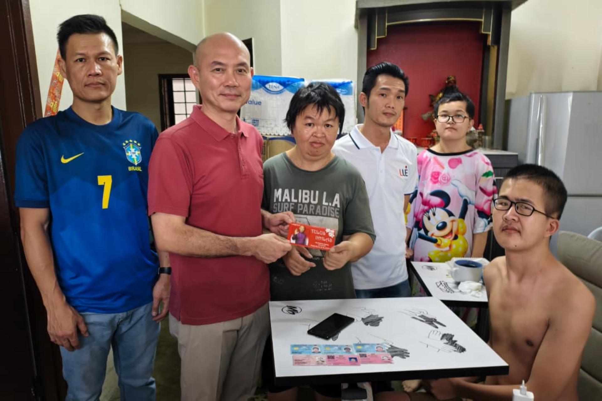 林立迎（左2）发放援助金给温女士，左起陈志杰、赖俊权和柯姓两兄妹。