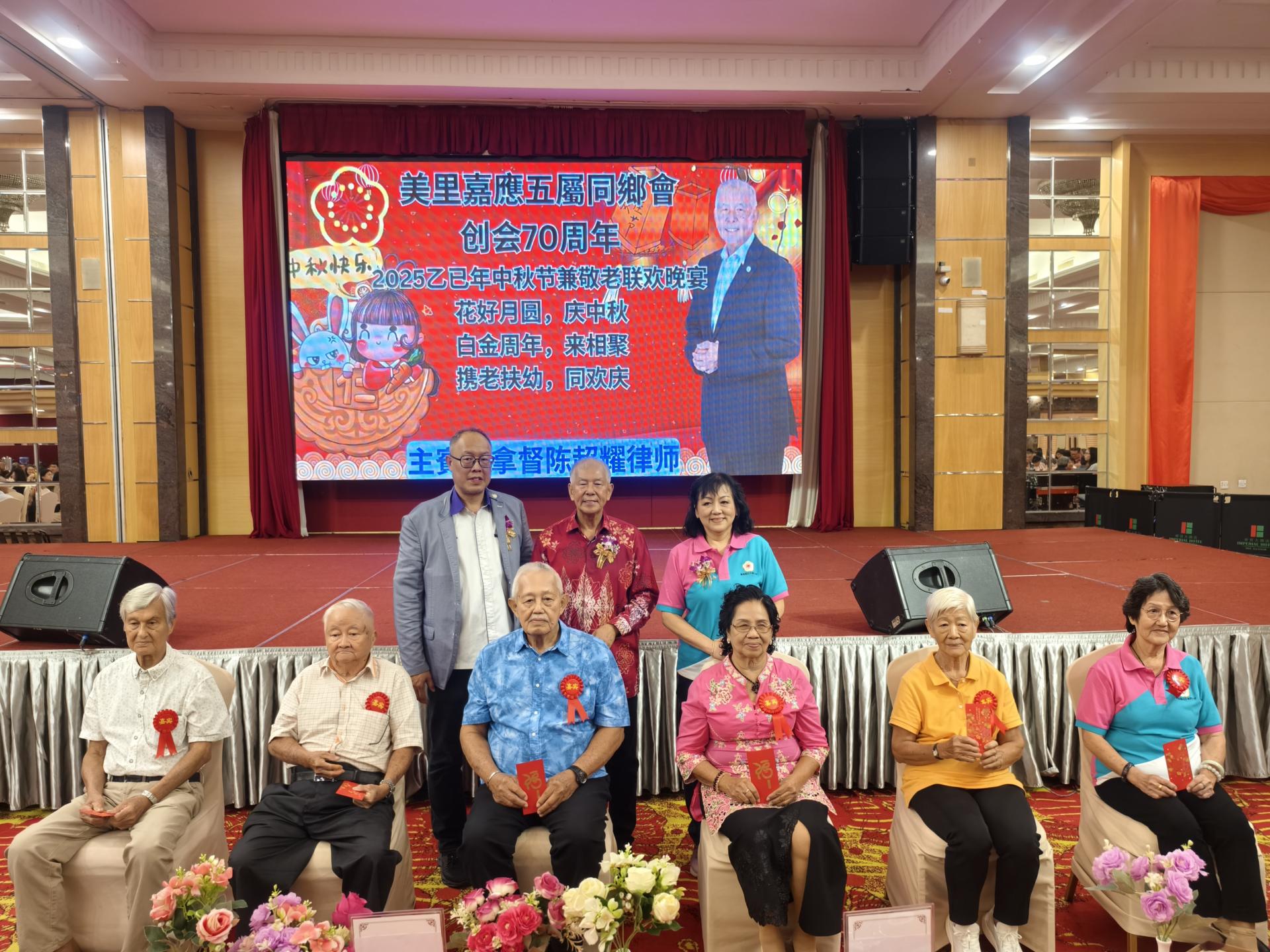 后排左起为美里嘉应五属同乡会主席甲必丹梁振林，主宾拿督陈超耀及筹备会主席古秋英，颁发红仪于最年长各3位男女会员合影。
