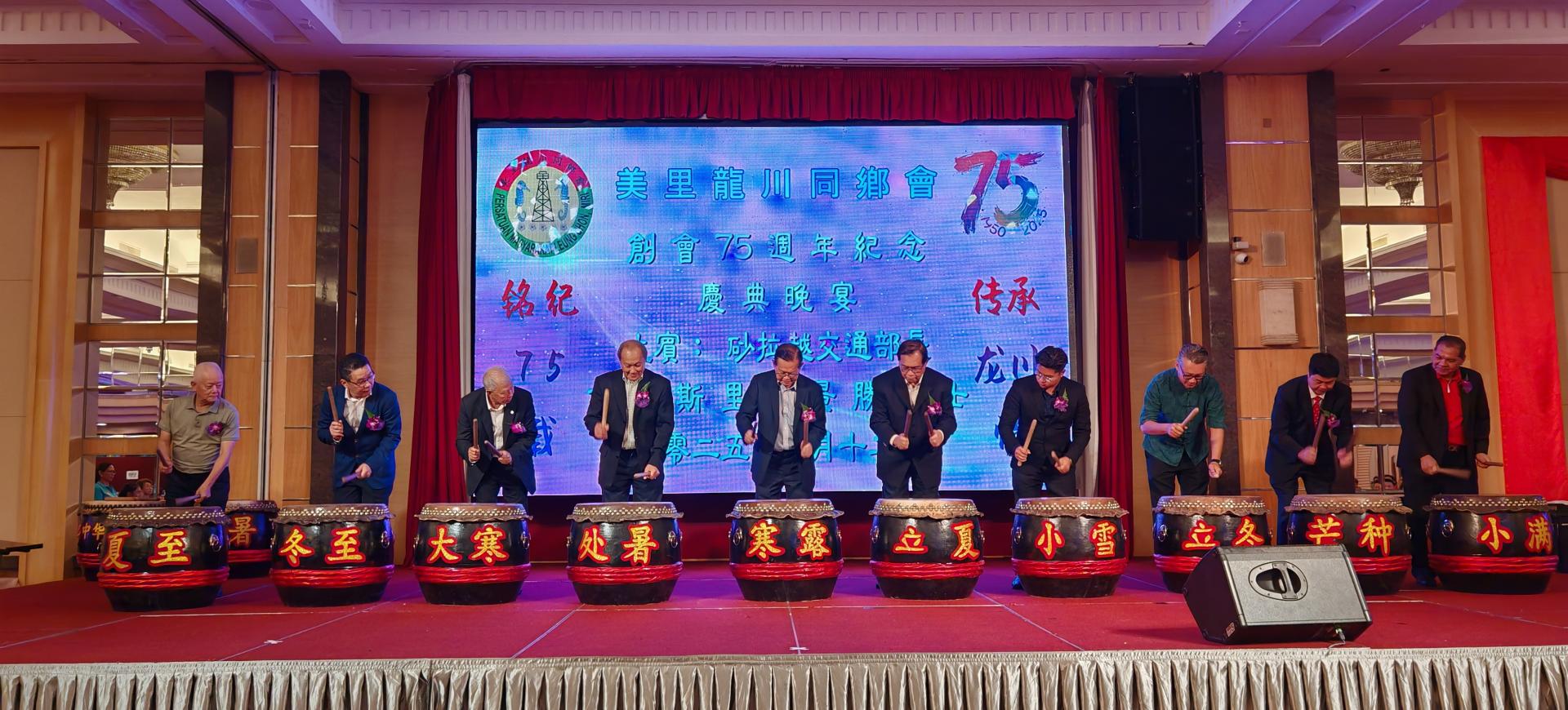 左起为中国深圳龙川商会代表叶德军、沙巴龙川联合会、马来西亚龙川总会会长兼全球龙川同乡联席会议副主席张斯量、砂旅游部副部长拿督陈超耀、筹备会主席黄居恒、砂交通部长拿督斯里李景胜、美里龙川同乡会主席杨日青、美里区国会议员赵俊文助理邹梓建、埔奕区州议员俞小珊代表兼美里市议员余忠明、全球龙川同乡联席会议副主席兼东莞龙川商会创会会长黄文辉，以及马来西亚河源同乡会总会长谭玉良，一同为美里龙川同乡会75周年庆晚宴击鼓开幕。