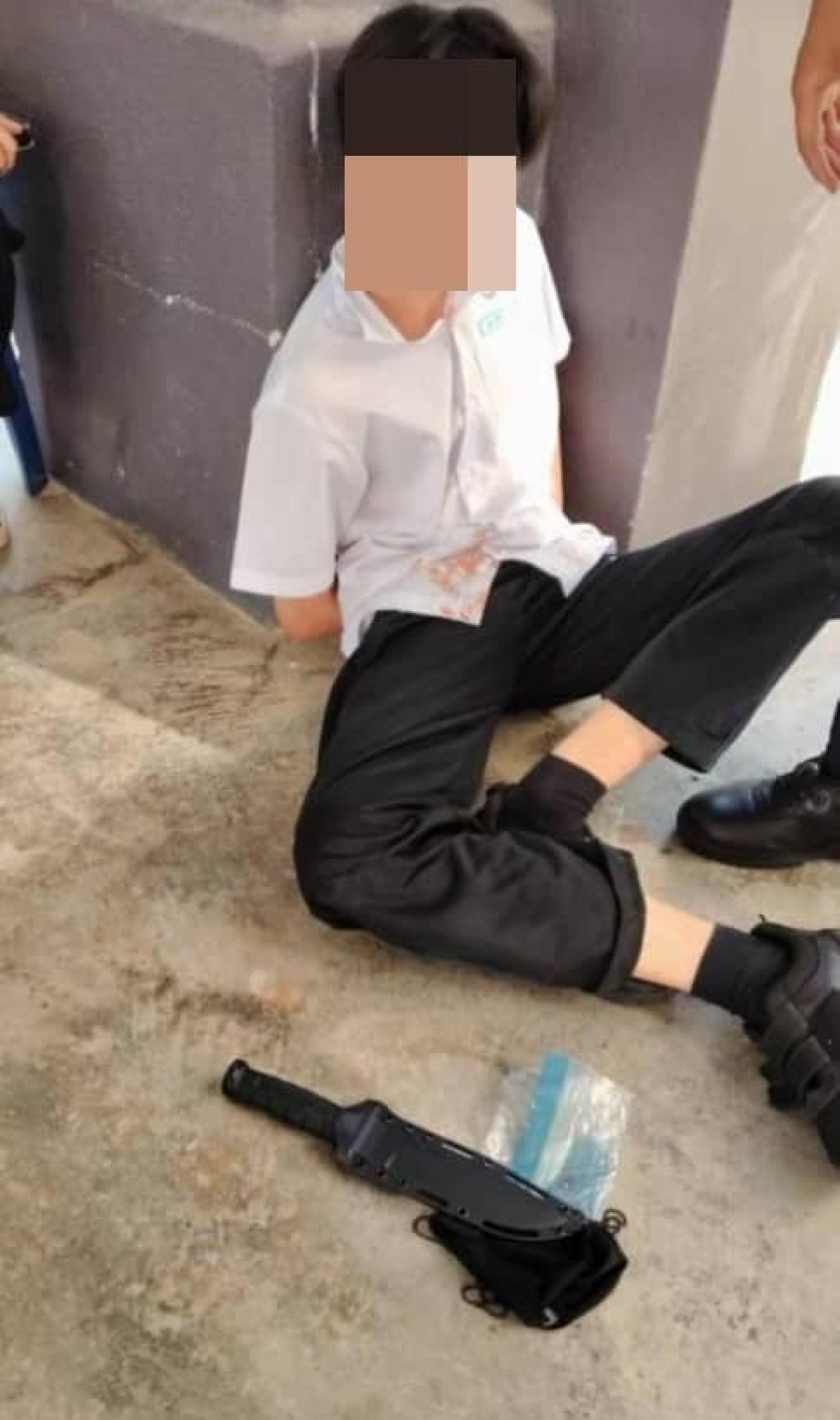 相信是嫌犯的学生被制伏在一旁，等候被警方带返警局问话。