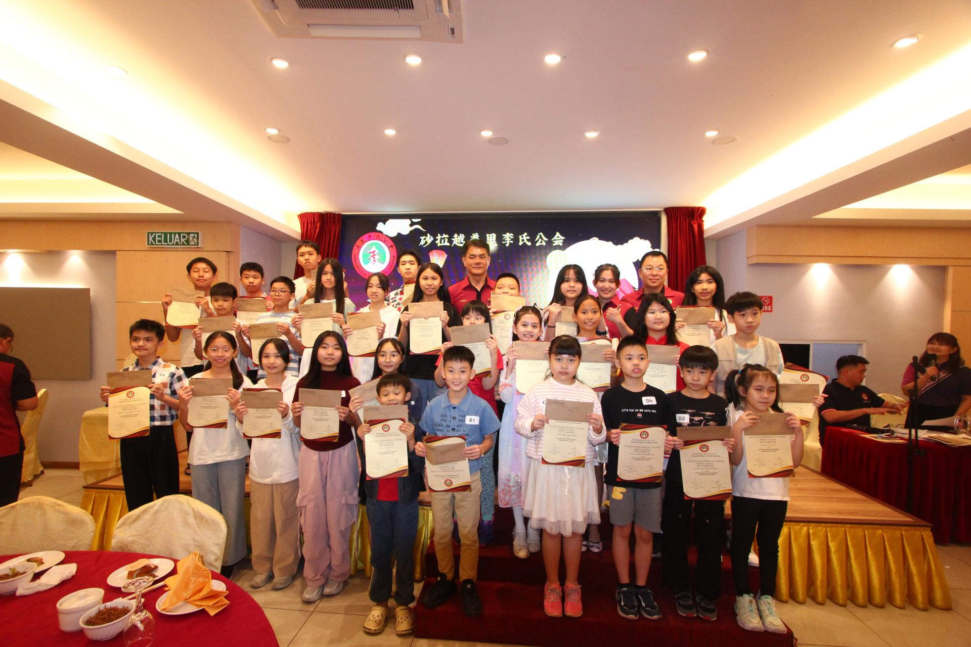 美里李氏公会2024年会员子女学优奖励金幼儿组及小学组得奖者合影留念。后排中者为主席李德意，右2起为教育组主任李天送及筹备会主席李殷稼。