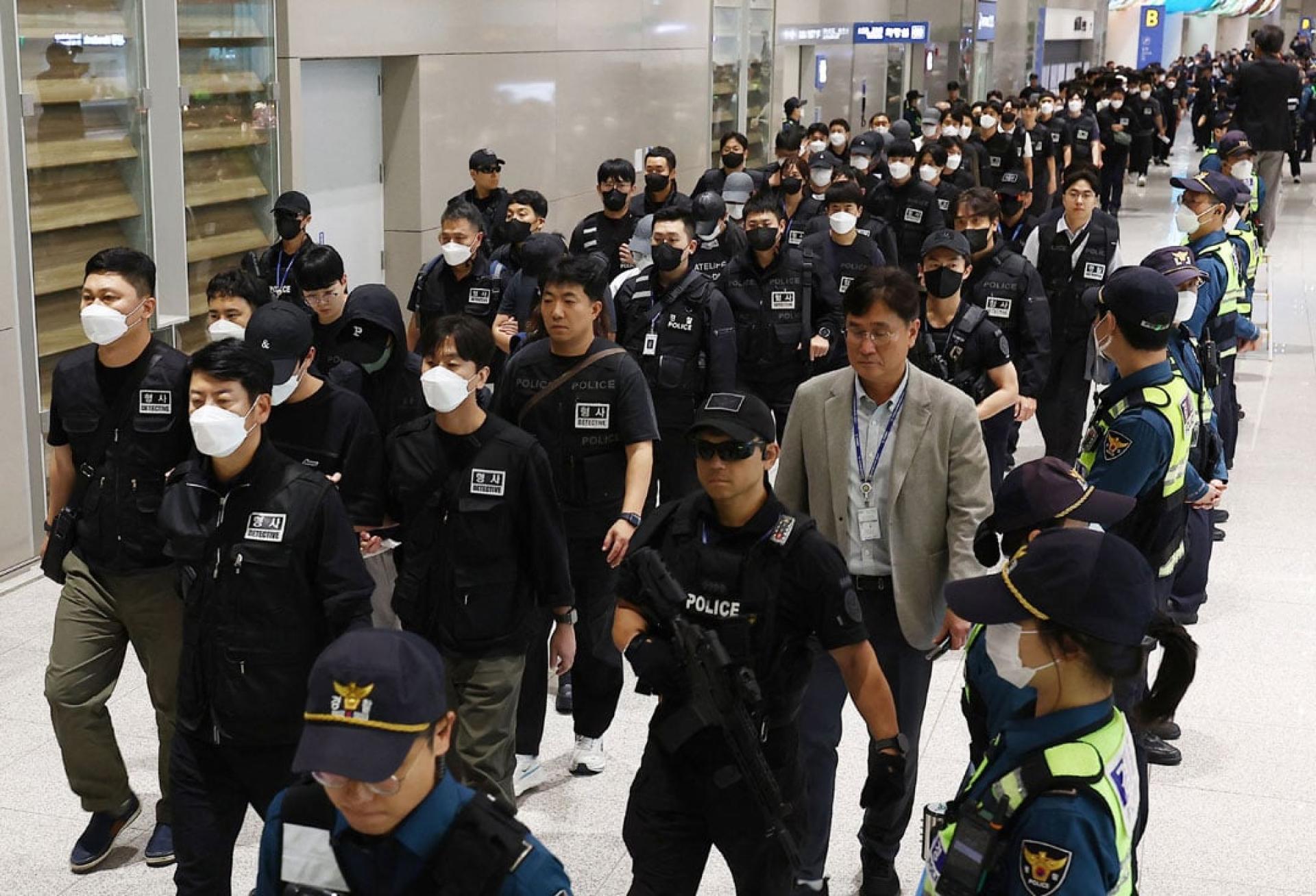 韩国执法人员在仁川机场押解涉诈人员。