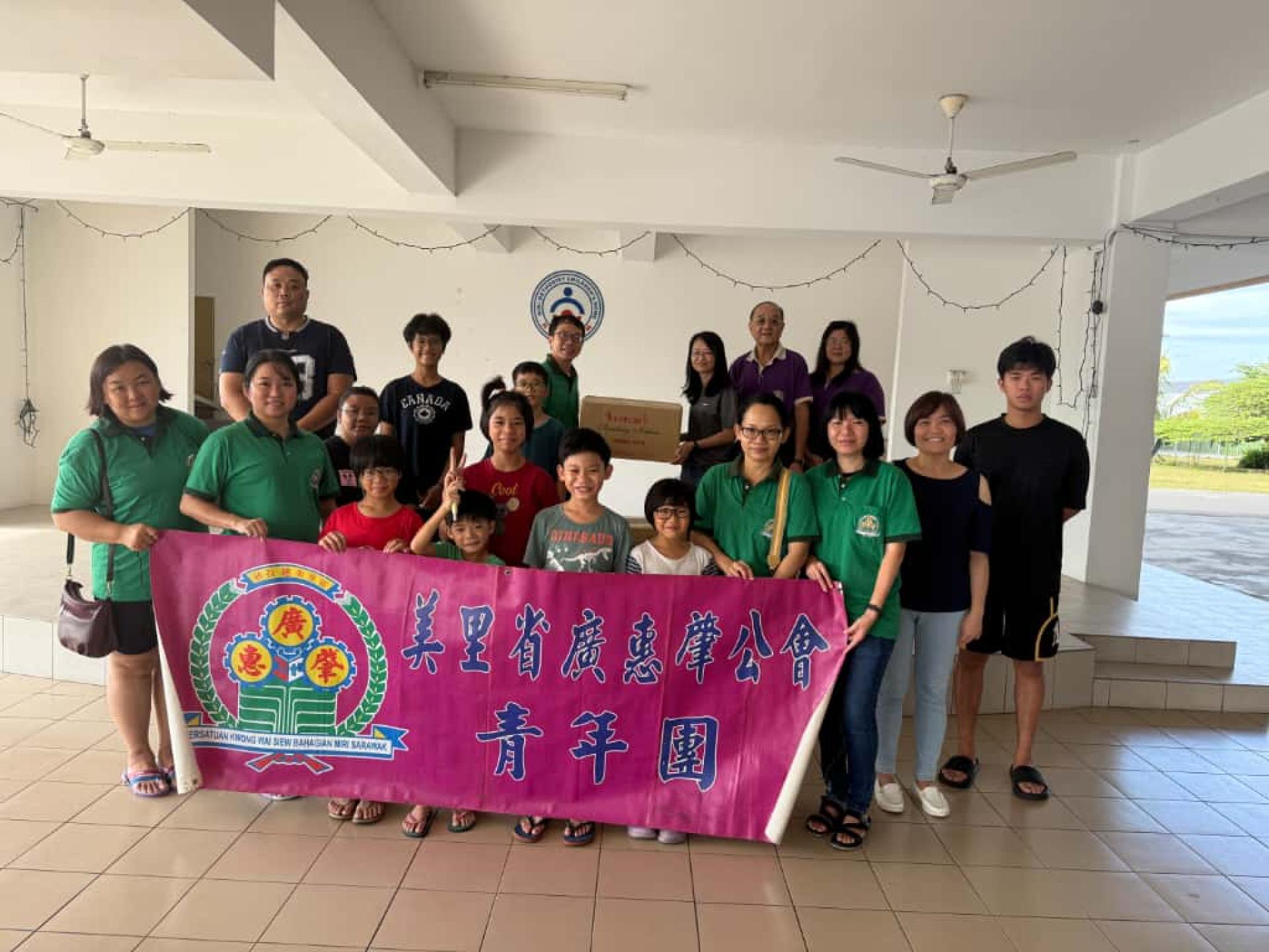 美里广惠肇青年团团长余伟顺（后排左1）移交卫生用品予“美里卫理福儿院”，由该院代表接收。后排右2为会长黄运祥。