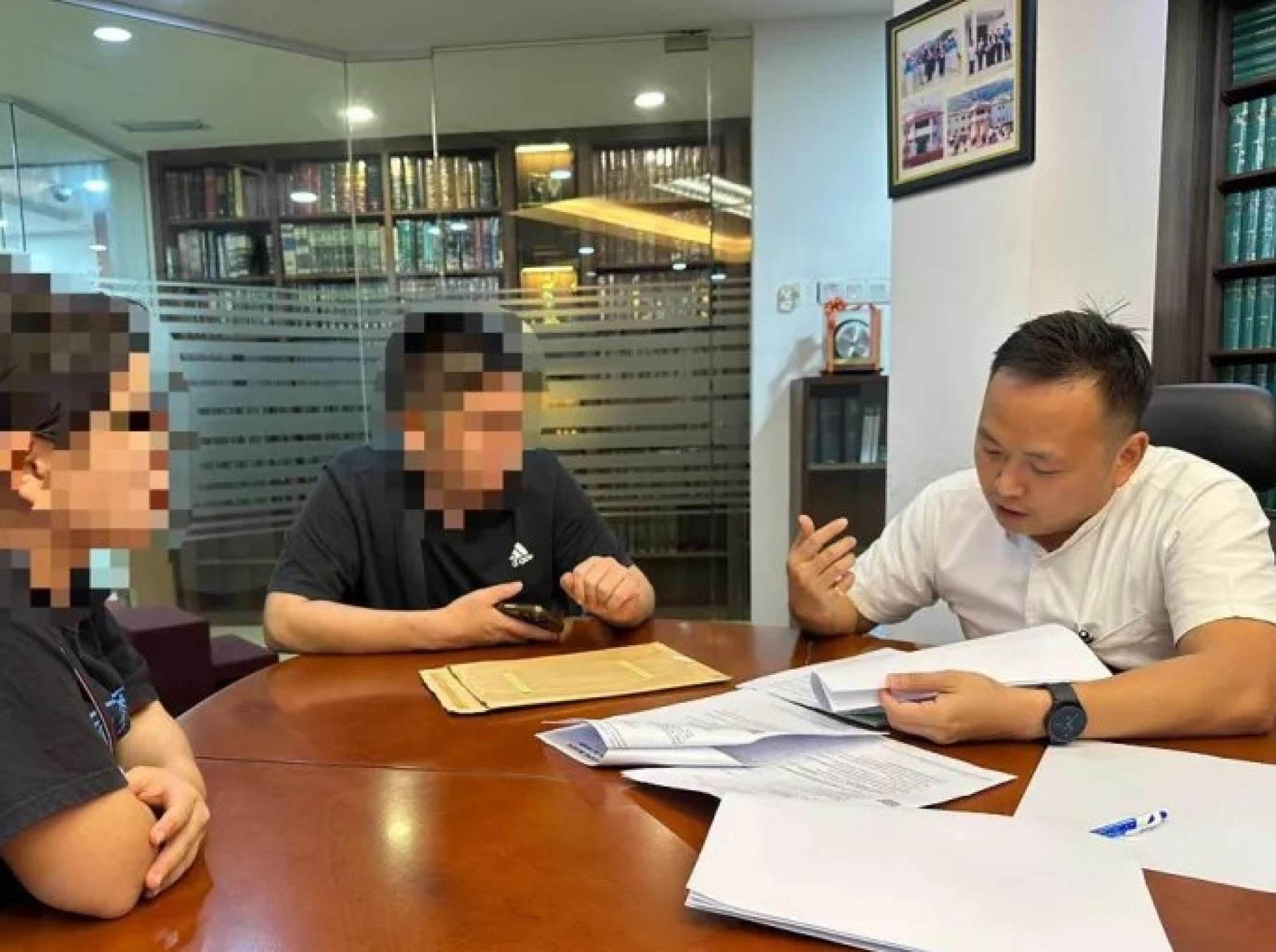 江峰年（右）于2025年10月27日与因大耳窿广告受害的男子交流。
