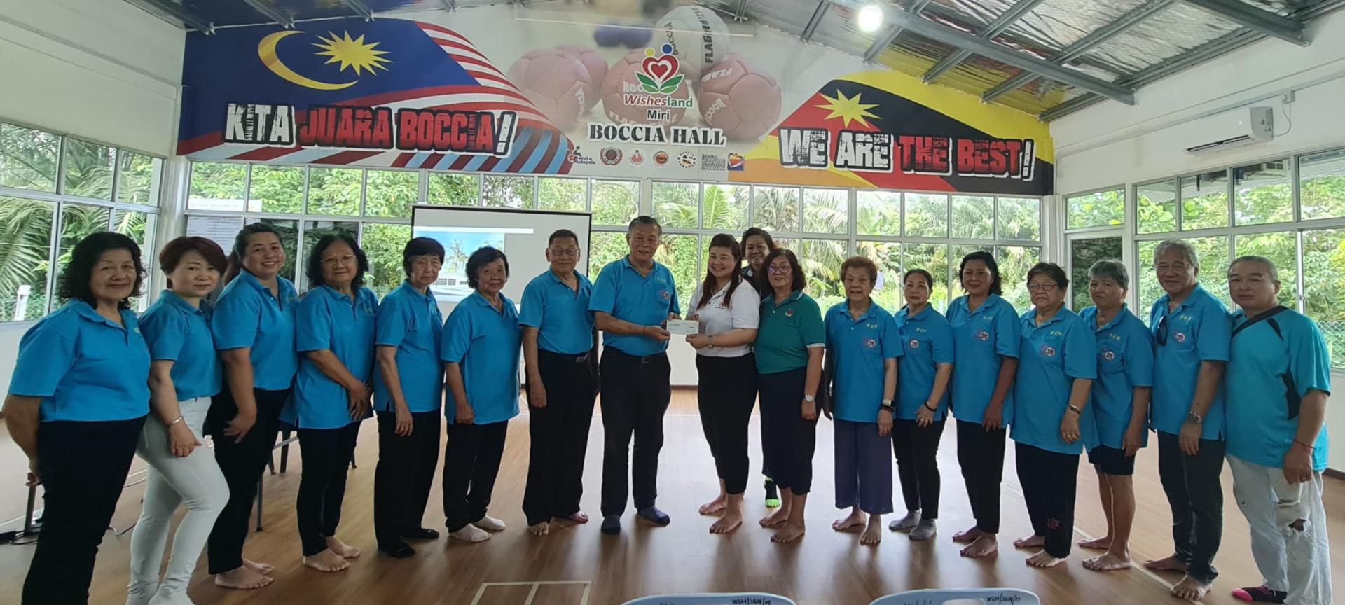 紫星閣閣長許爲隆(左8)移交5000令吉支票予美里唯心樂園代表接收。右爲婦女組主任沈燕蓮(右5)。