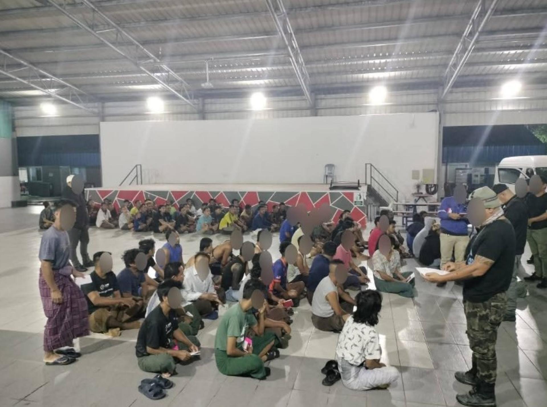 执法人员在现场围捕外籍工人并进行身份文件检查。