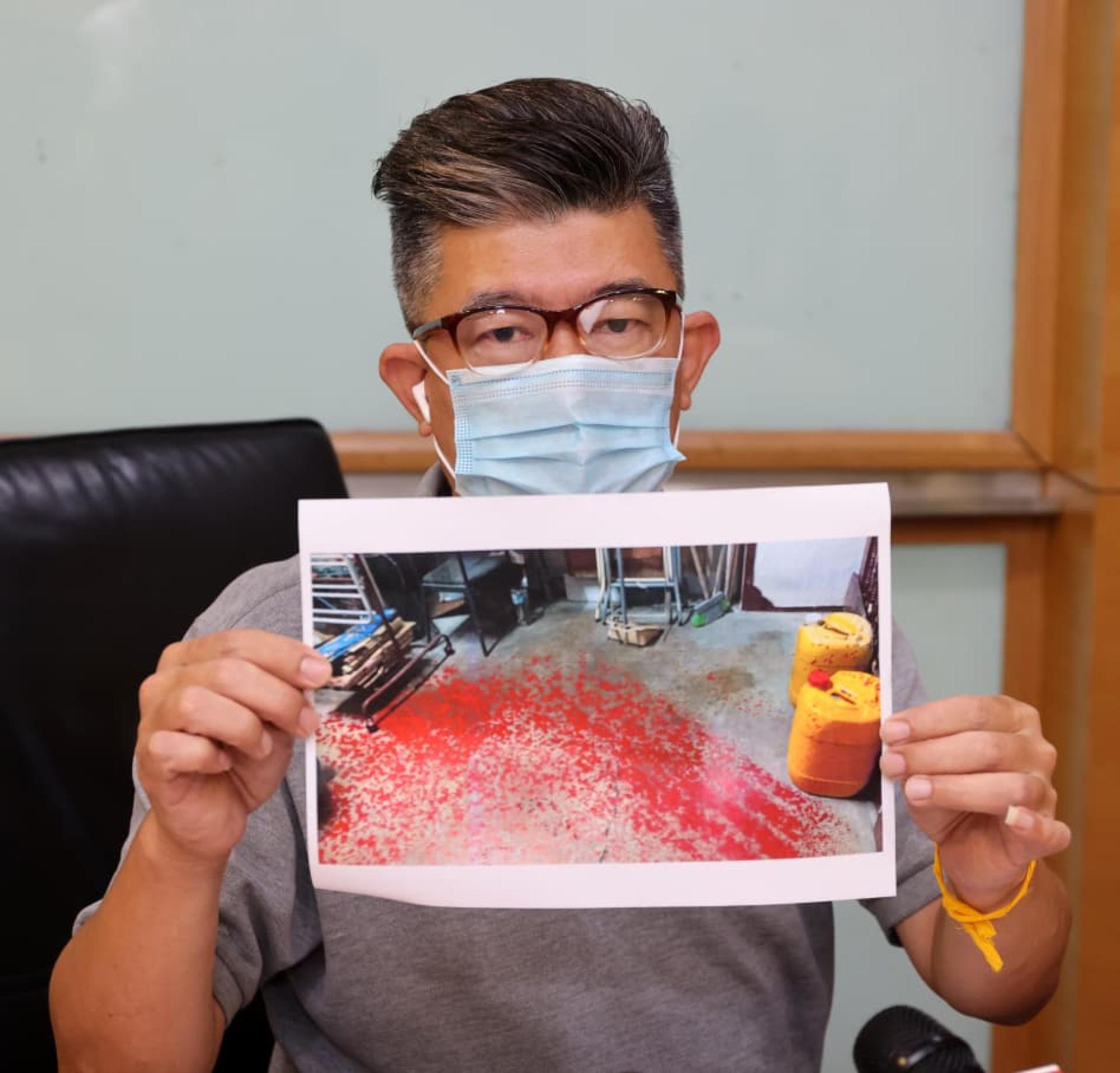 事主手持住所遭泼红漆的图片。