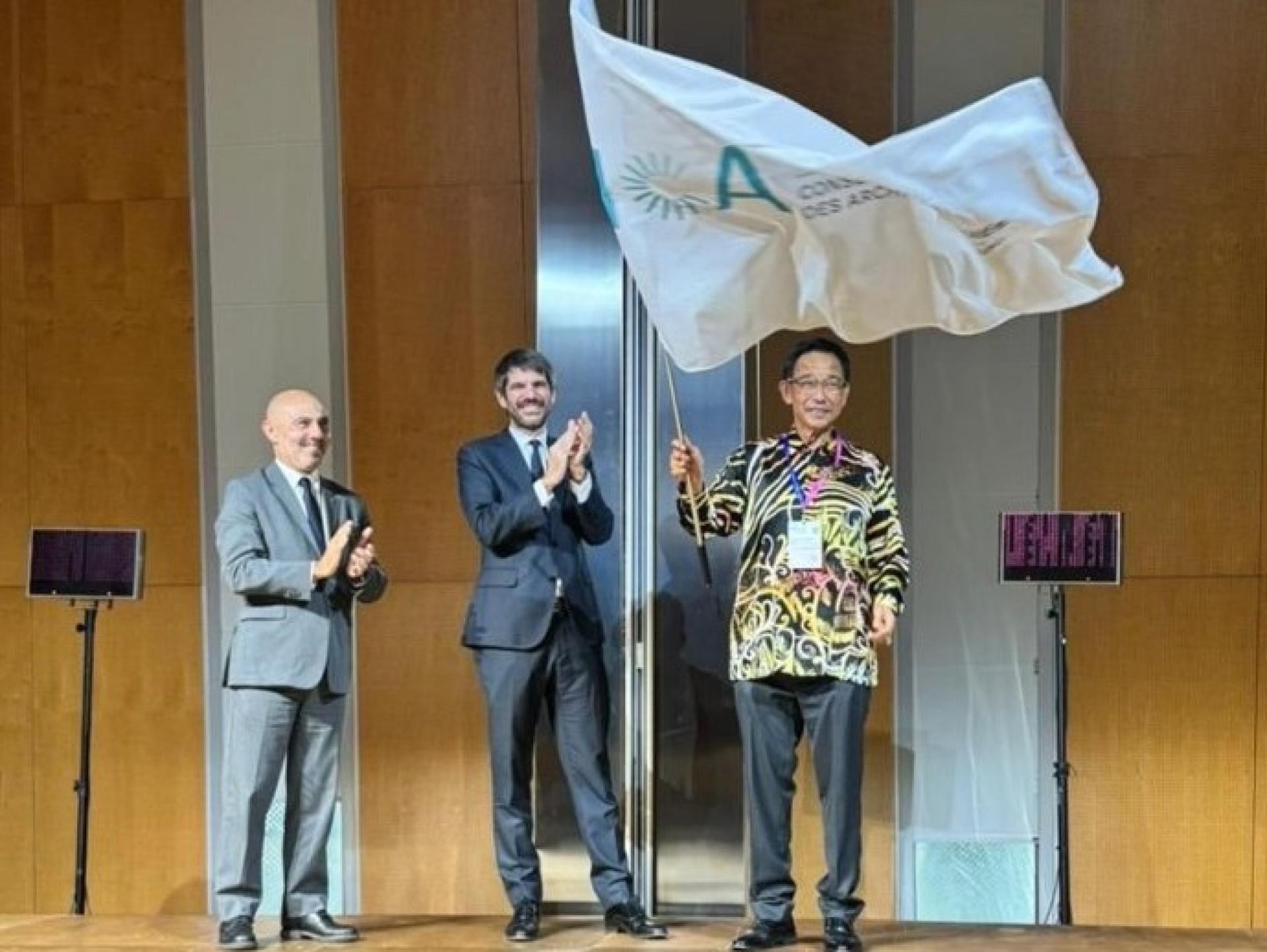 阿都卡林（右）在西班牙巴塞罗那举行的交接仪式上接过旗帜，象征国际档案理事会大会主办权正式移交予马来西亚砂拉越。