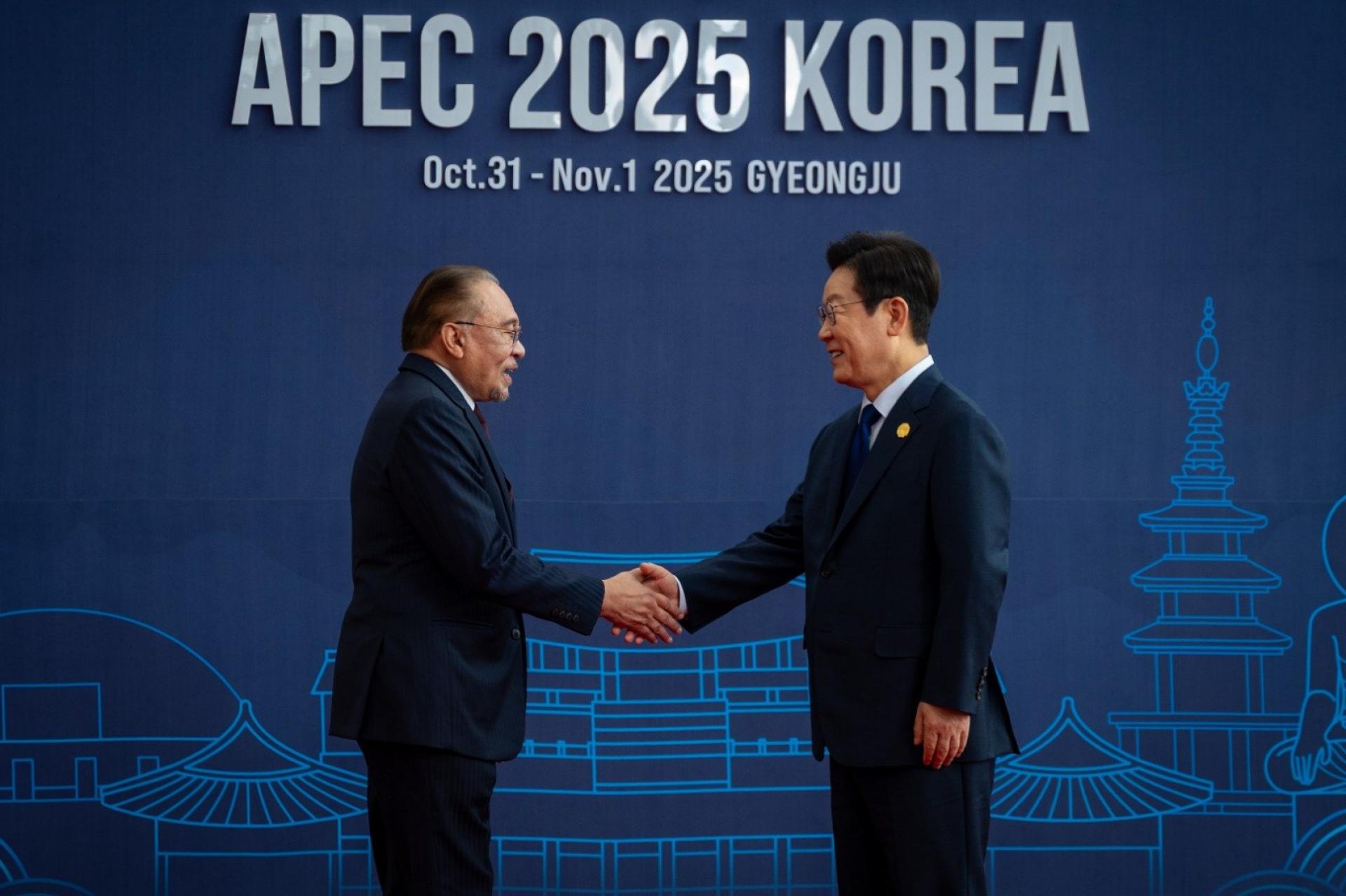 安华(左)与李在明握手寒暄。(马新社图)