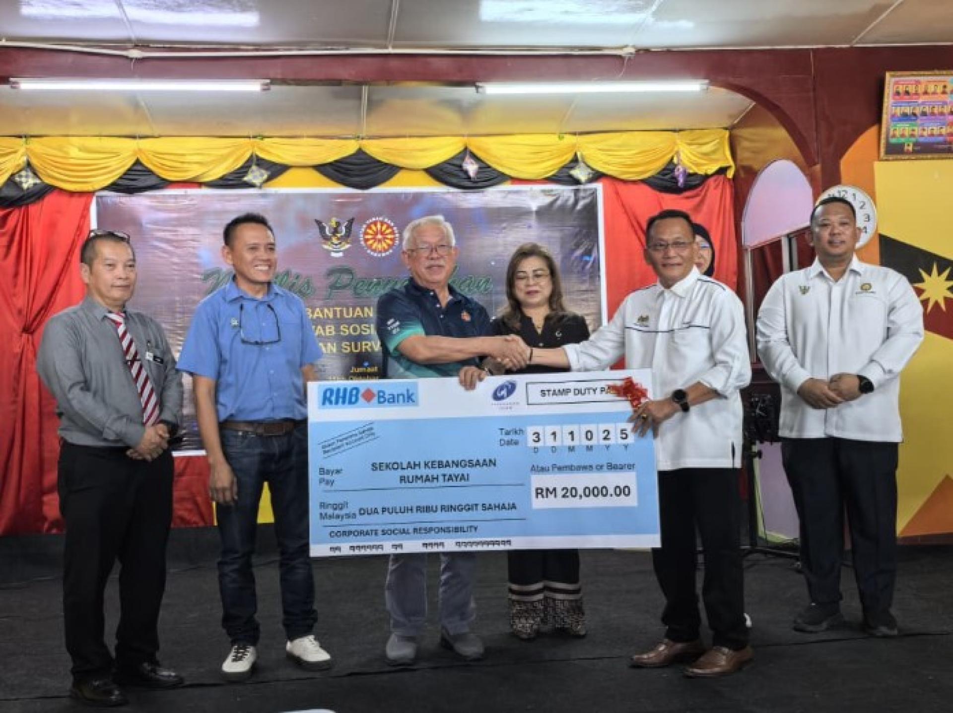 约翰西基移交模拟支票予学校代表。