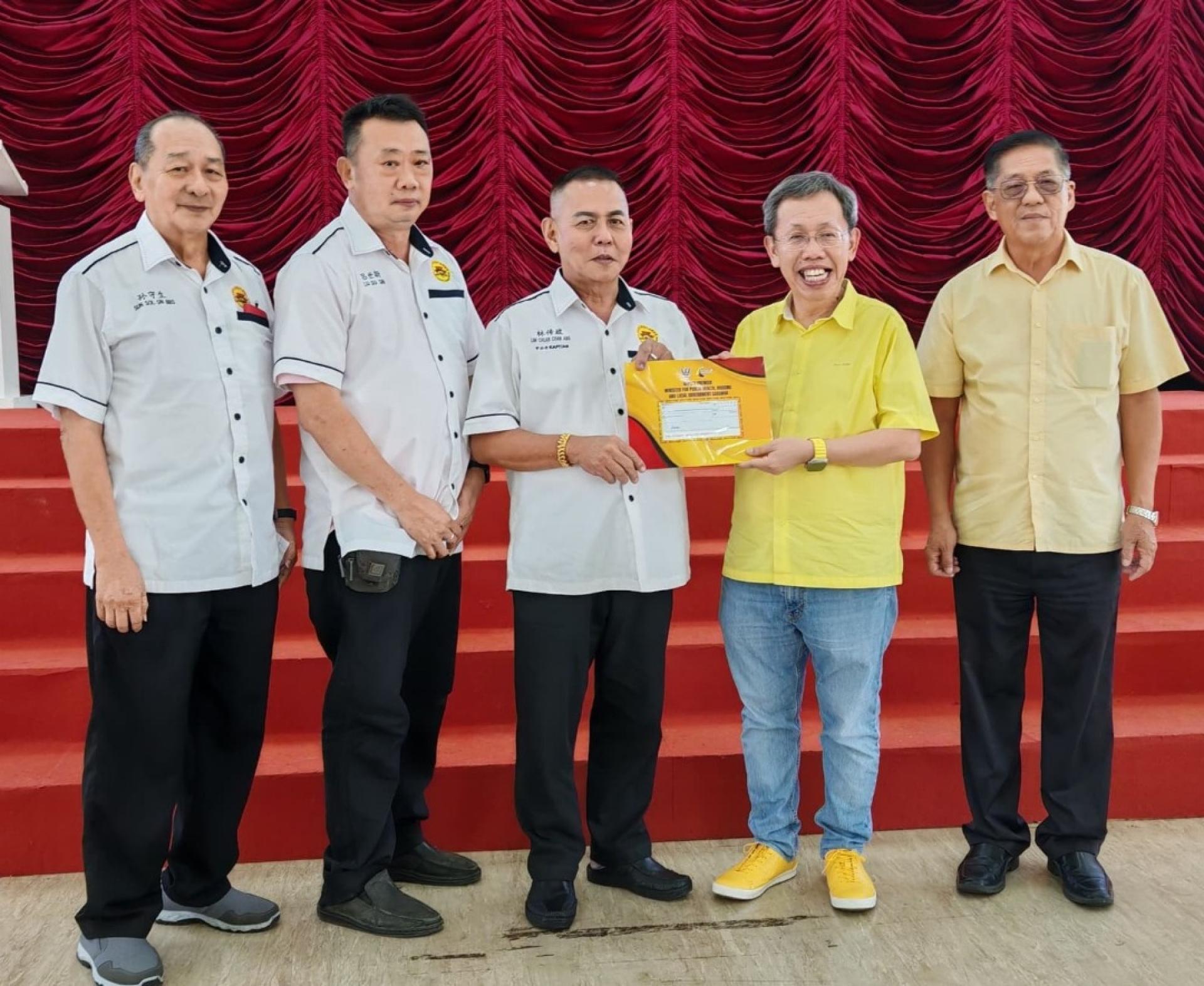 甲必丹林传政（左3）由沈桂贤副总理手中接过古晋老巴刹民众联谊会拨款。左起为该会秘书孙守生、理事吕世新；右是天猛公拿督陈如飞。