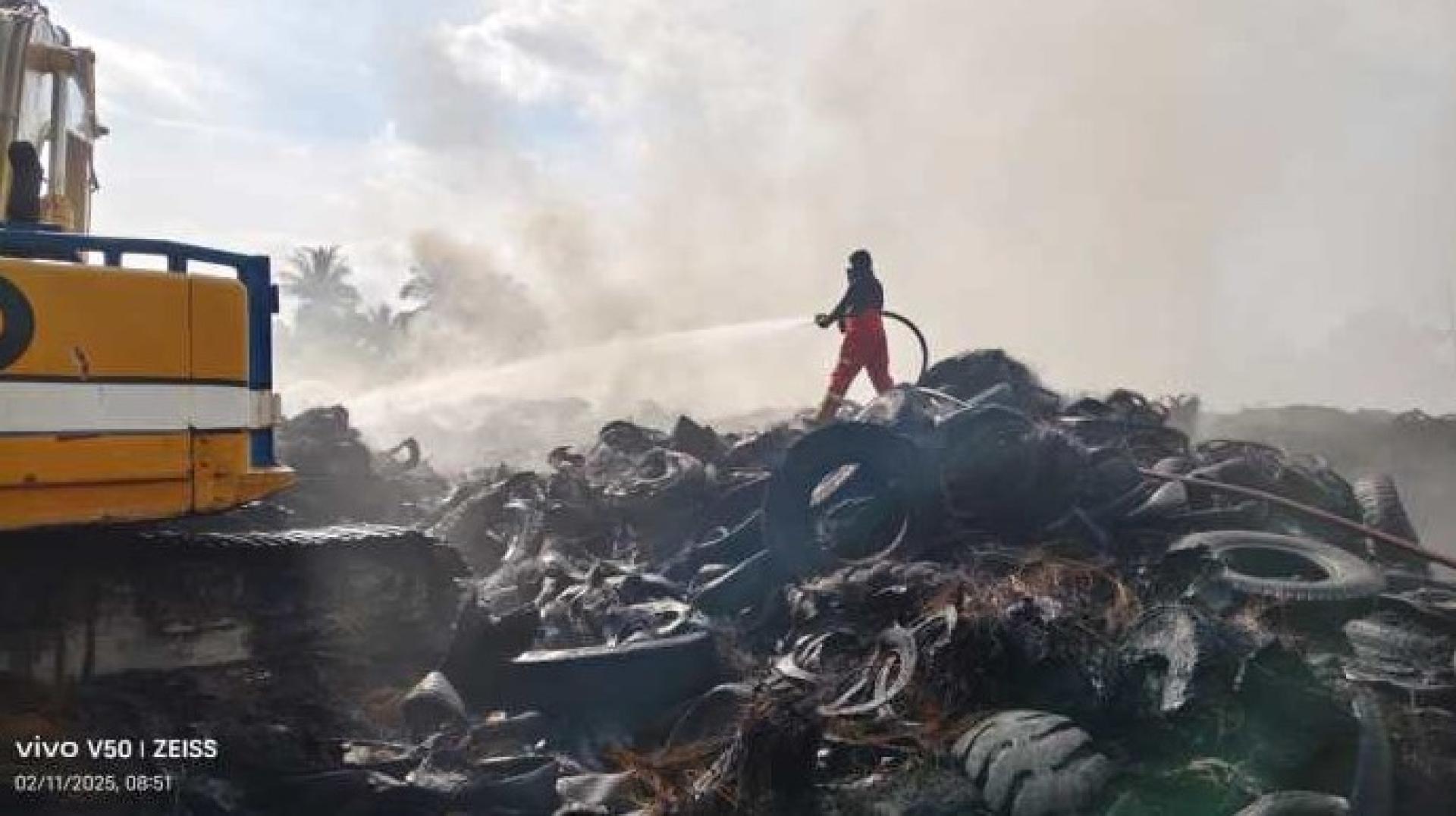 消防员于2025年11月2日在古晋－西连路9哩现场奋力翻动被烧焦的轮胎堆，持续寻找并扑灭残余火点。