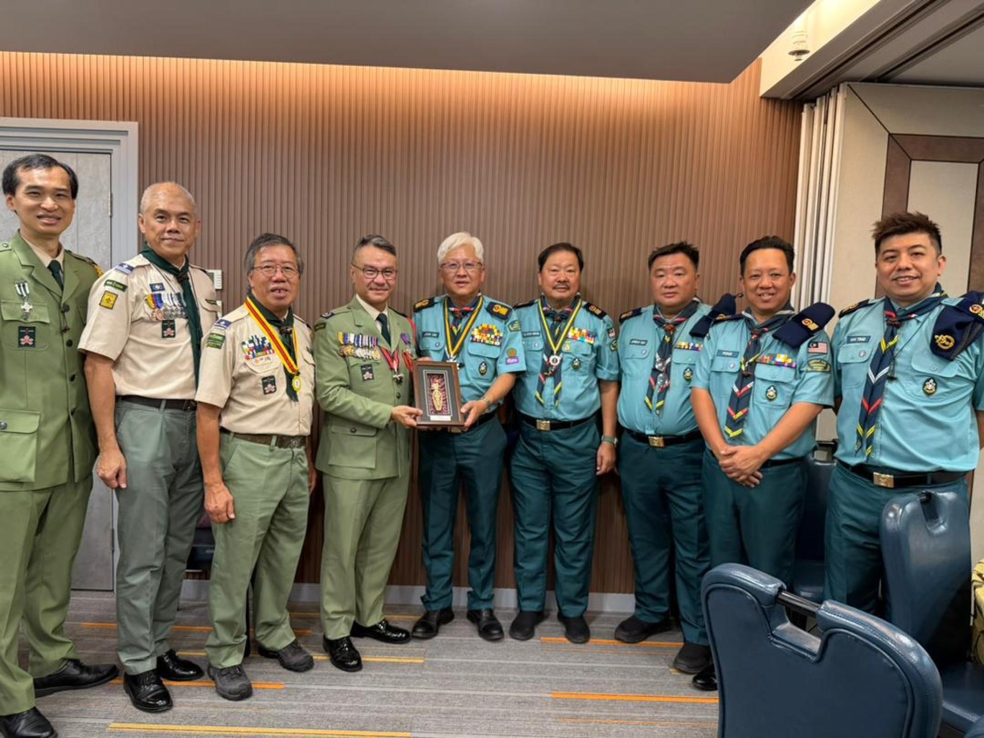 在代表团团员见证下，砂拉越首席童军总监林文明（右）向香港童军总会总监黎伟生博士（左4）赠送纪念品，象征双方深厚的友谊与合作精神。