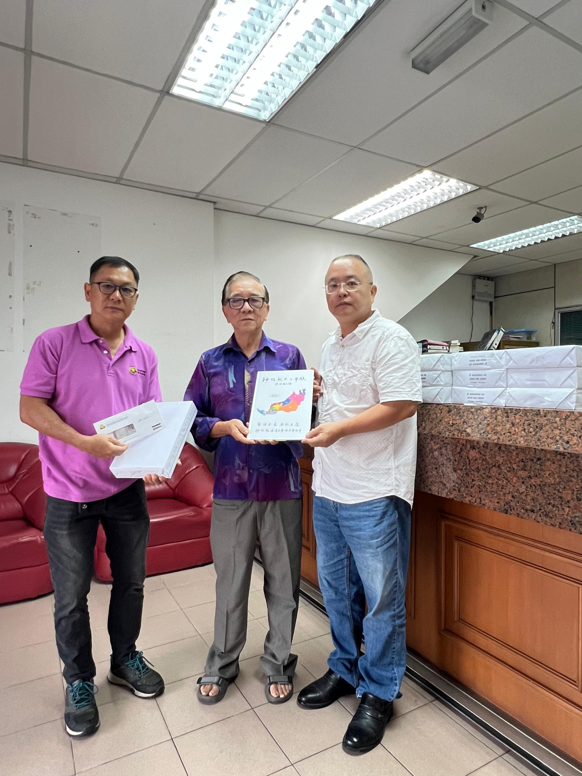 砂拉越南大校友会会长刘炳华（中）移交《砂拉越大小市镇》刊物予美林省华小董联会代表黄敬明（右）与黄汉强（左）接收。