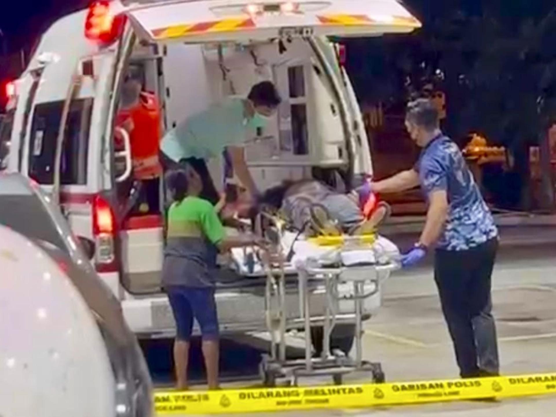 医务人员把伤者抬上救护车。