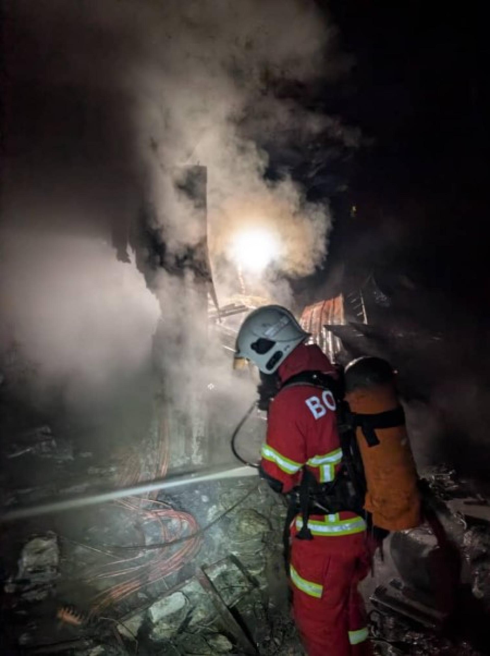 消防员在火灾现场奋力扑灭堆放建筑材料的火势。