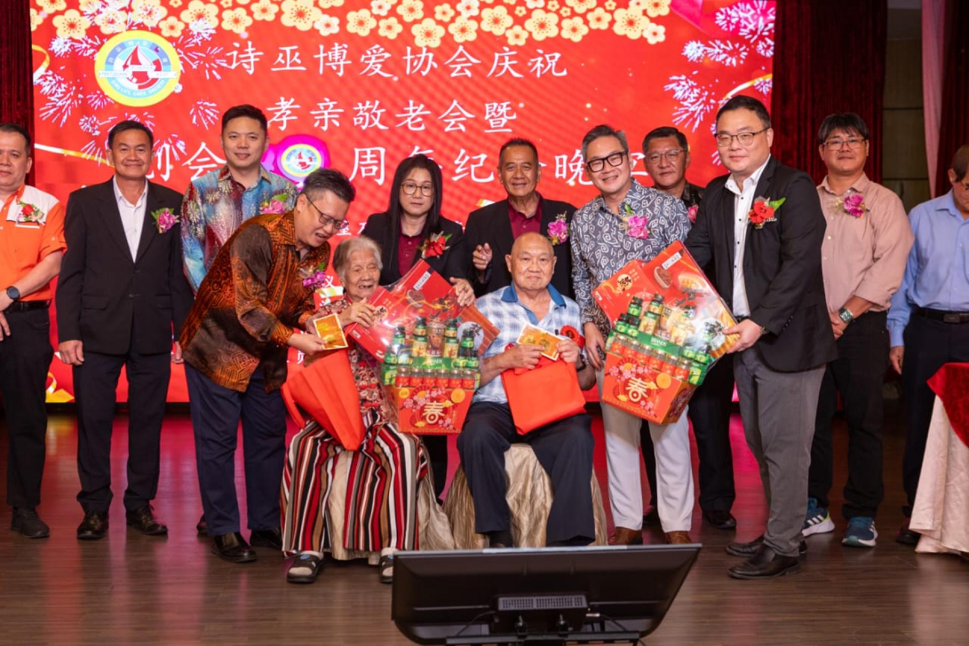 程明智（右）和武吉阿瑟区议员钱进一（左）分别赠送礼品给最年长男女寿星。