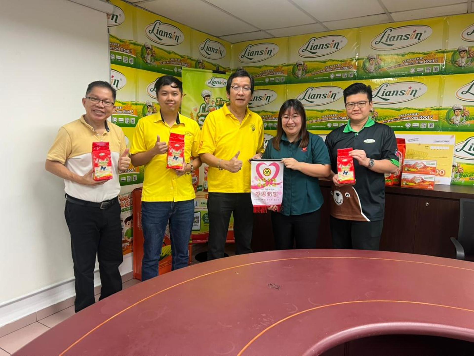 筹备会顾问凌德胜（中）移交感谢锦旗予同成发稻米贸易有限公司市场发展执行员丘紫霞。