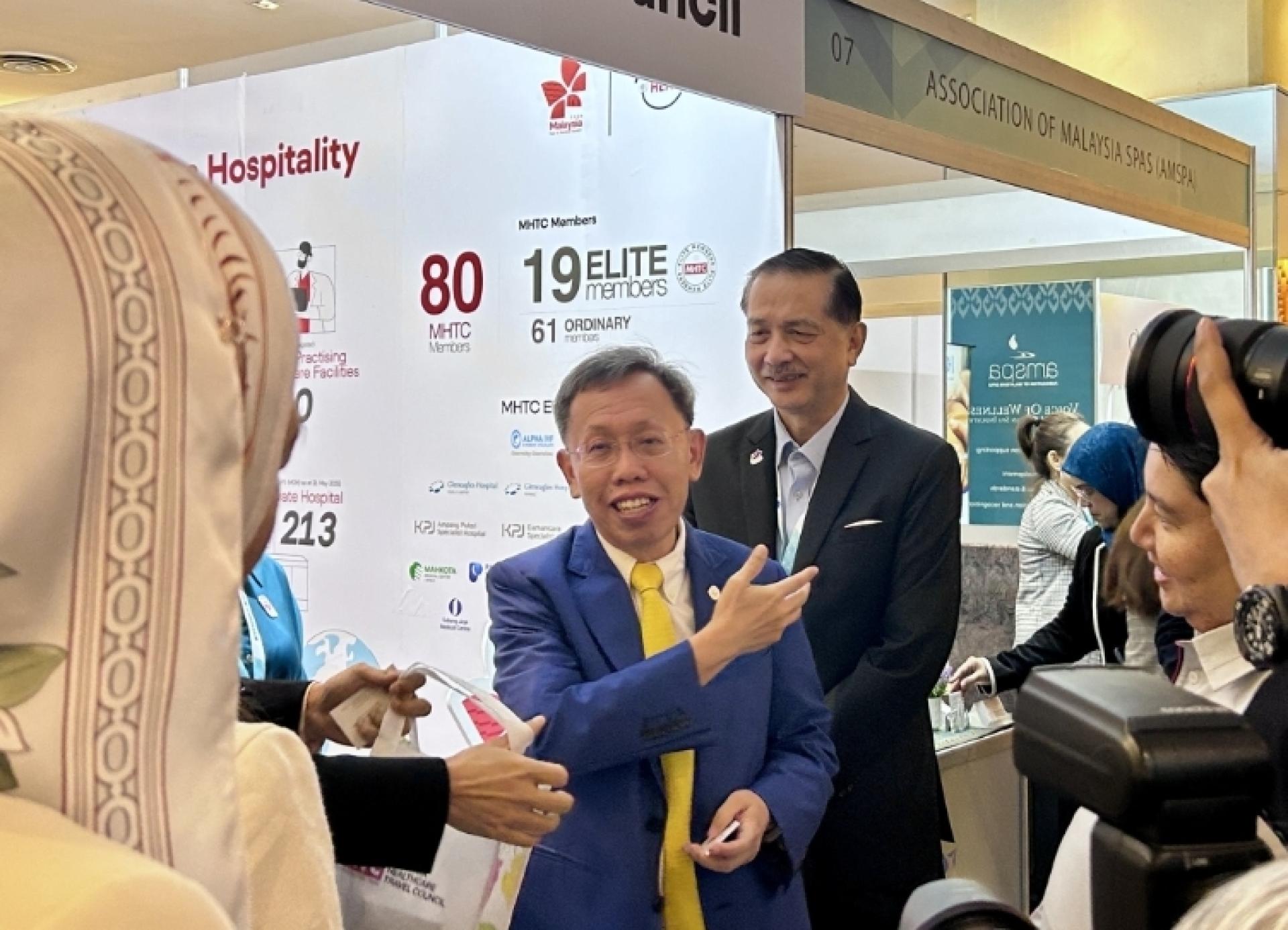 沈桂贤受访时影。其后我国为前卫生总监诺希山。