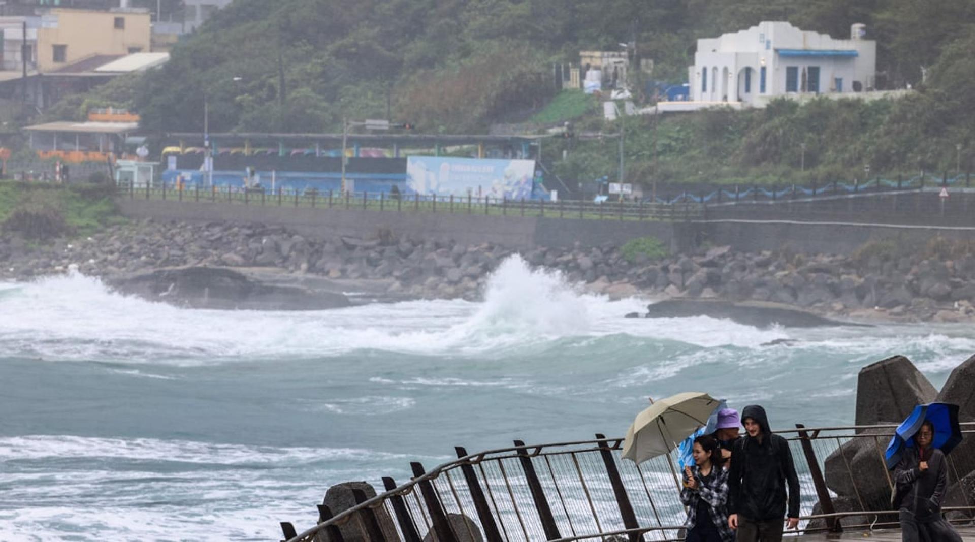 台风“凤凰”10日逼近台湾基隆市，人们撑伞抵挡风雨。